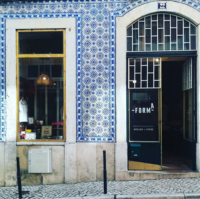 Front of a building with blue and white decorative tiles, large windows, and a sign reading '-FORM A ATELIER + STORE'.