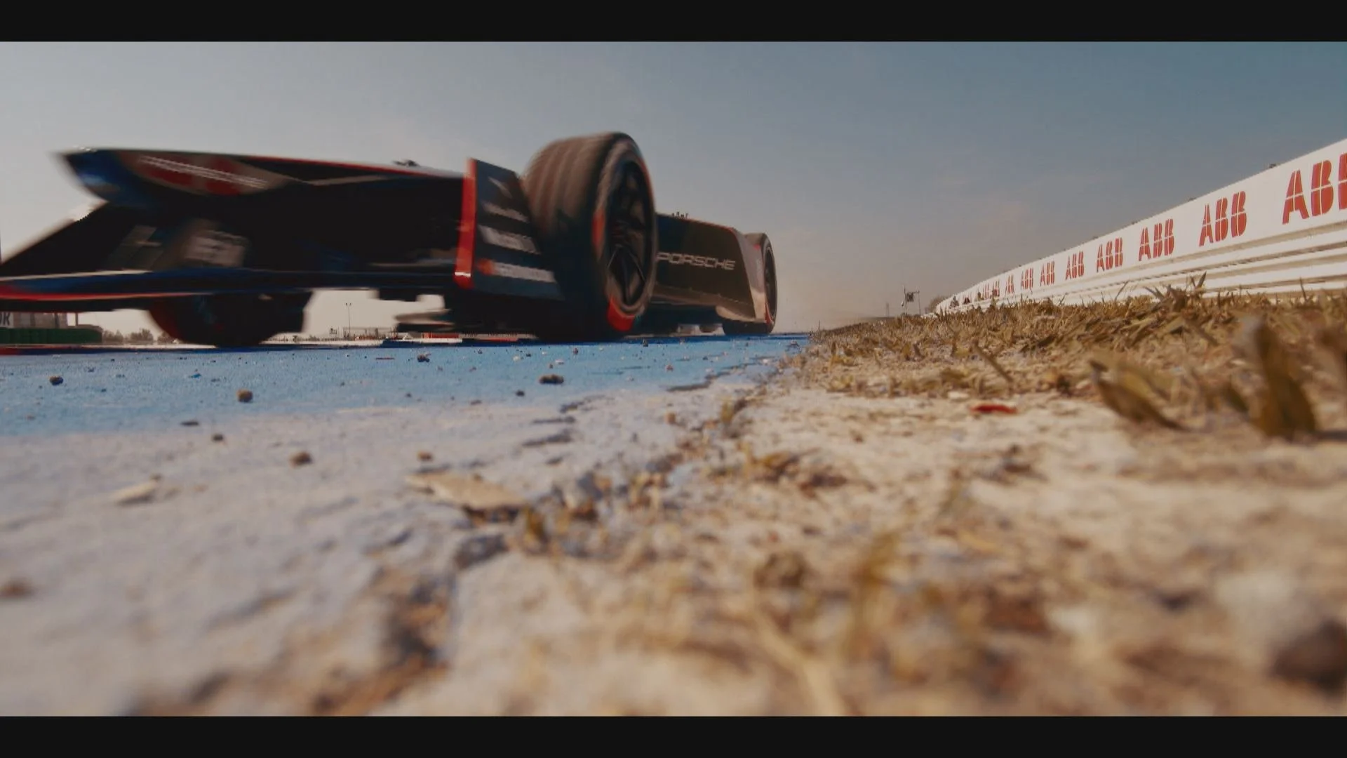 A race car on a track viewed from a low angle near the ground.