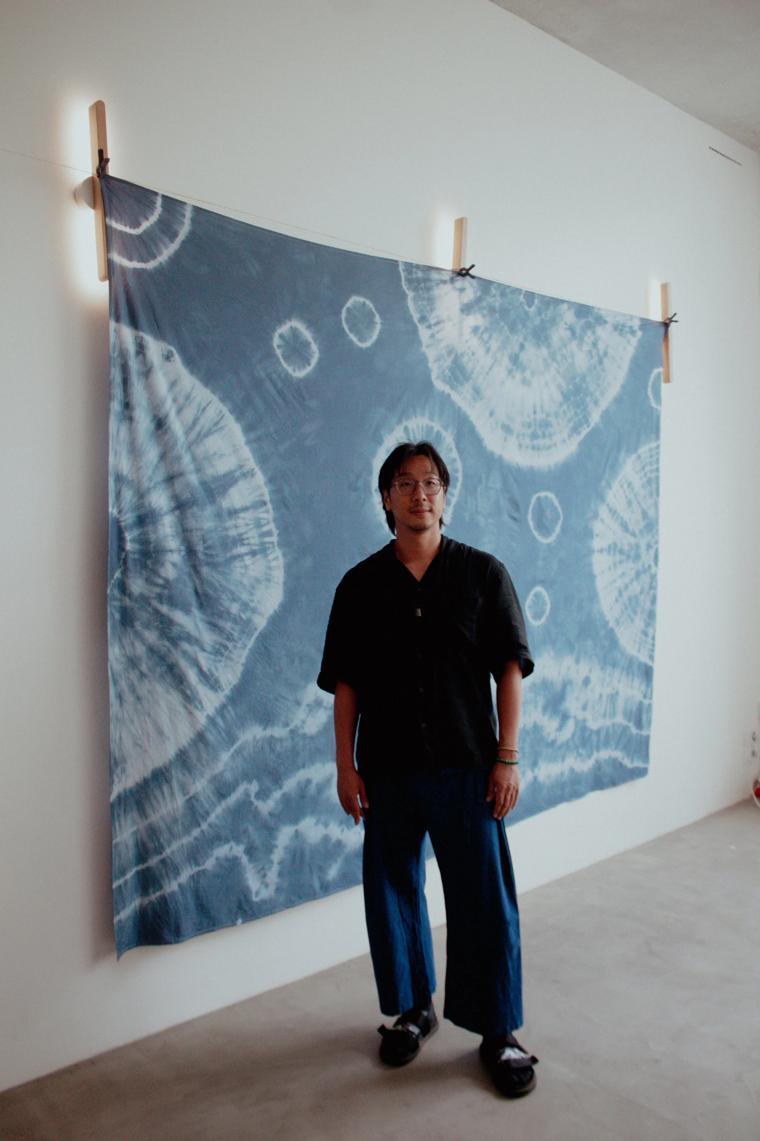 Un homme se tenant devant une toile d'art abstrait dans un musée, portant des vêtements décontractés, avec des lunettes.