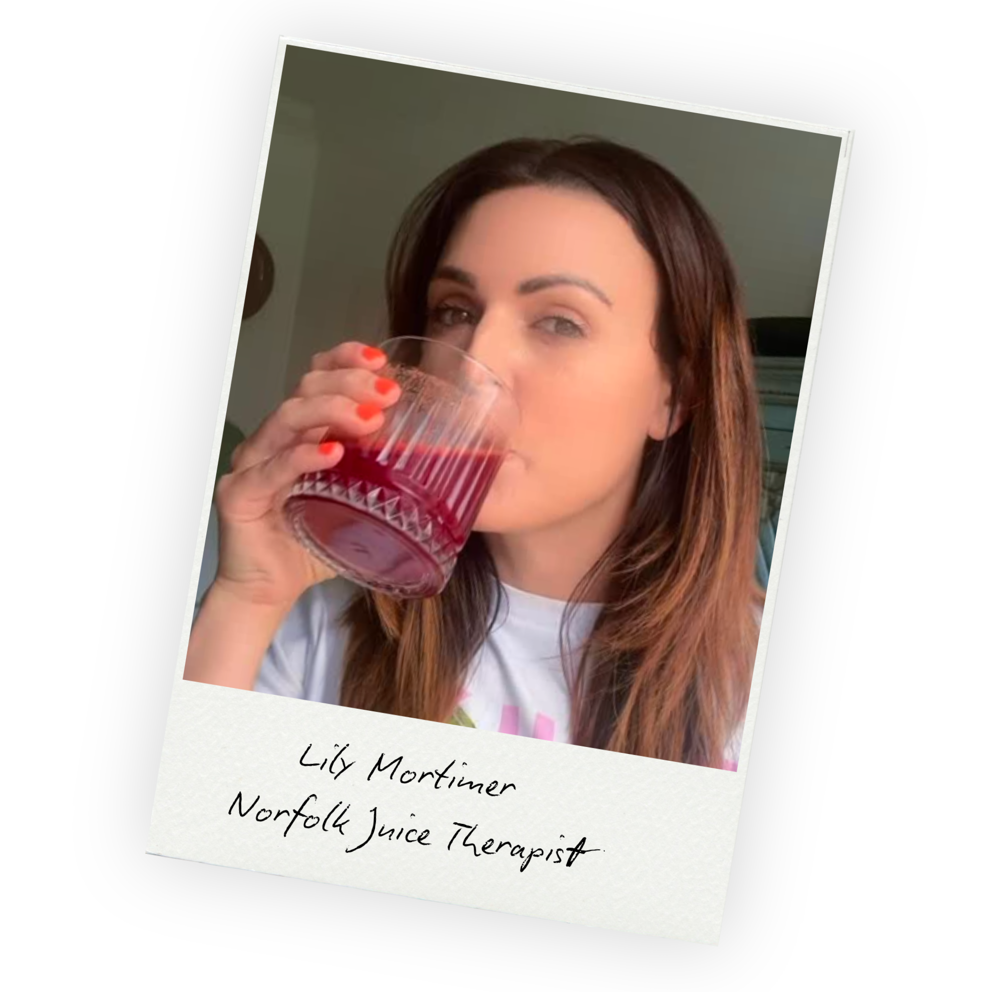 A woman with long brown hair and light makeup is holding a clear glass of red juice and smiling at the camera. The photo is slightly tilted, and there is a handwritten note underneath that reads 'Lilly Mortimer Norwich Juice Therapist.'