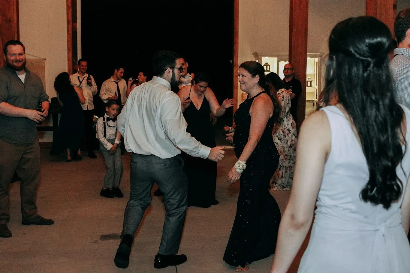 People dancing and enjoying music at an indoor party or wedding reception.