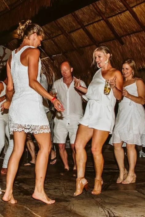 Group of people dancing and having fun at a party or celebration in a room with wooden ceiling.