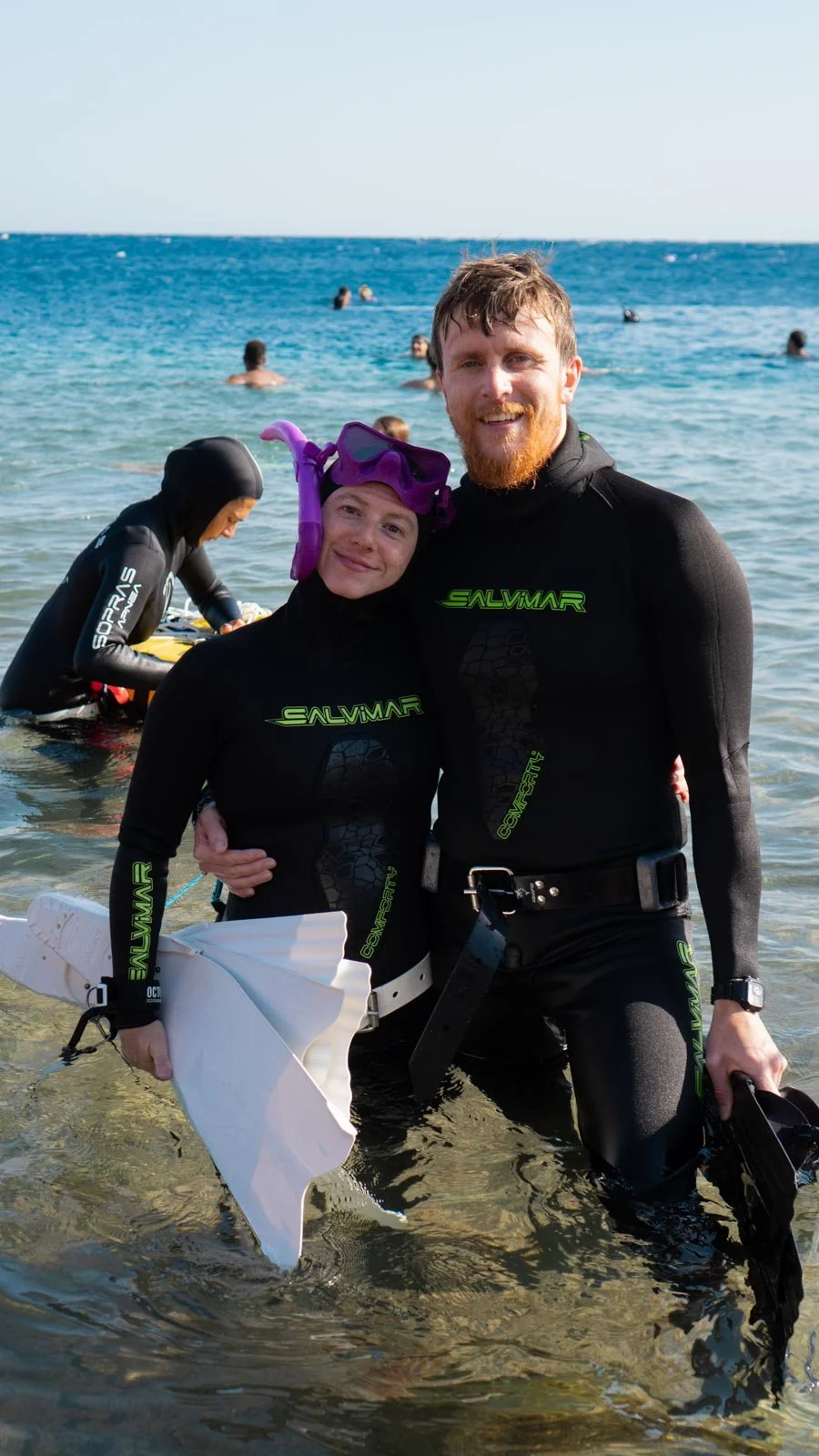 two freedivers smiling for a photo in the red sea, wearing full gear