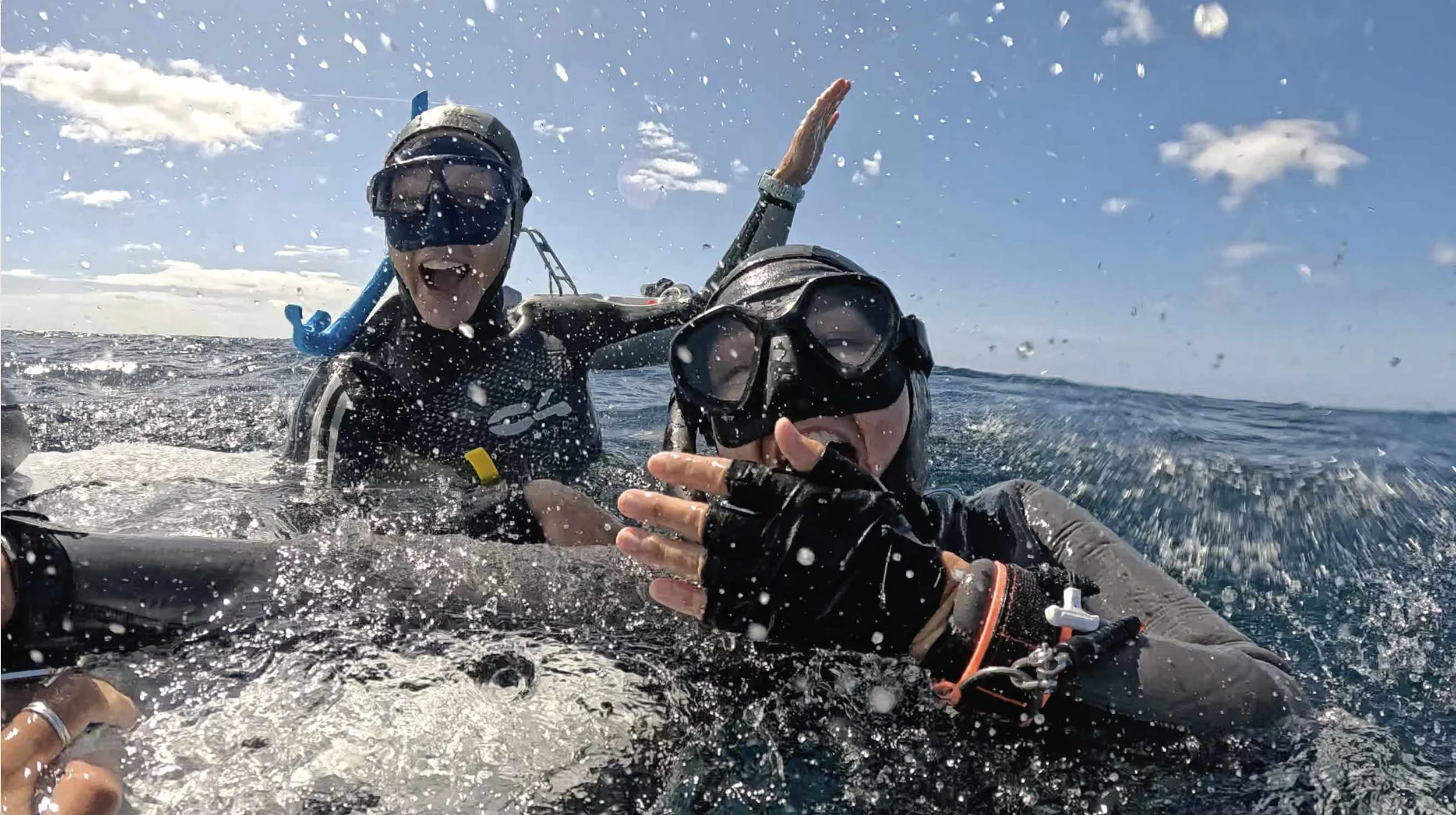 two freedivers splashing, grinning, to celebrate a PB around the buoy at sea