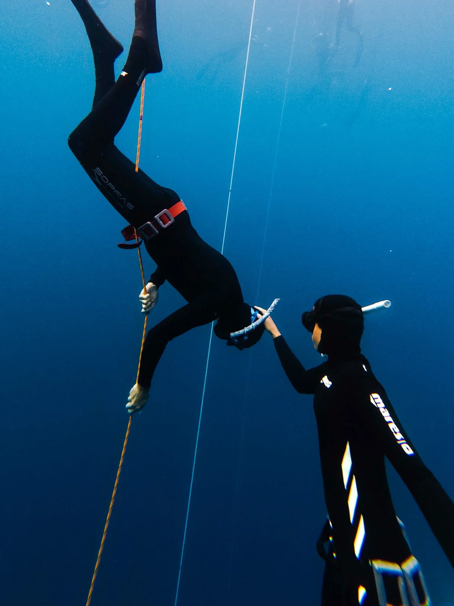 Beginner freediver with instructor line training, with instructor gently adjusting their free immersion head positon.