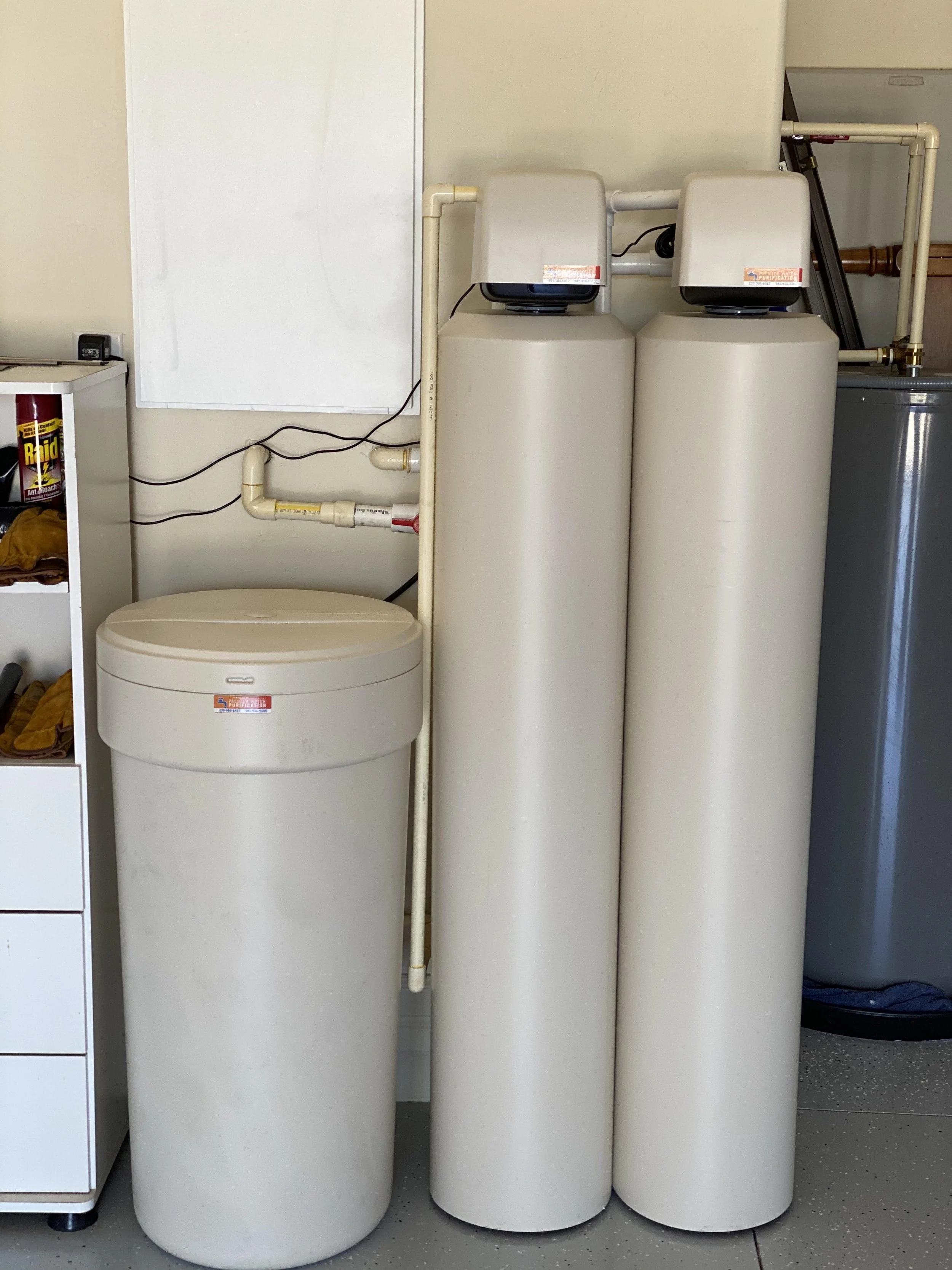Water softening or filtration system with three large tan tanks in a garage 