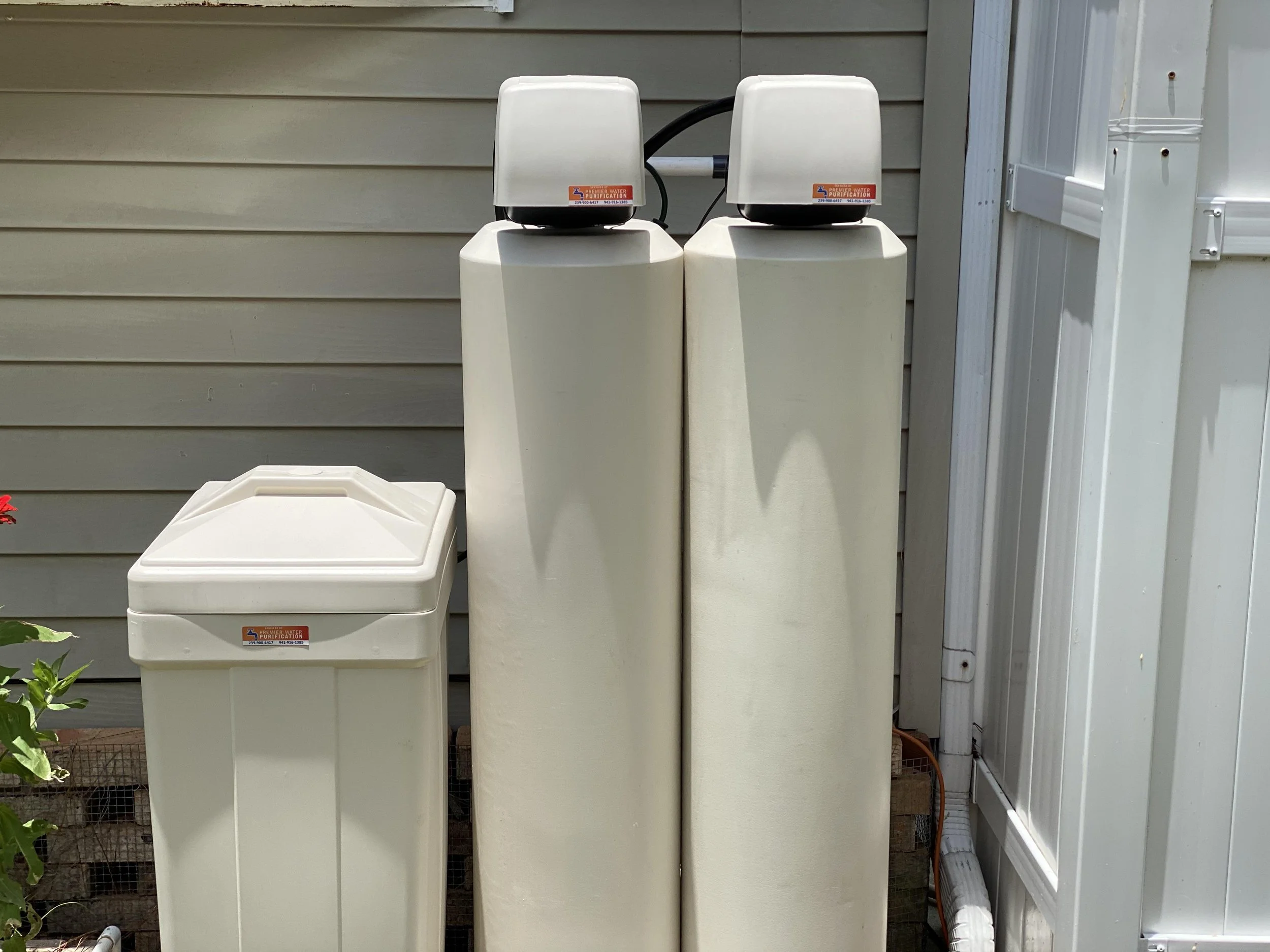  water filtration units are installed outside against a beige wall. 