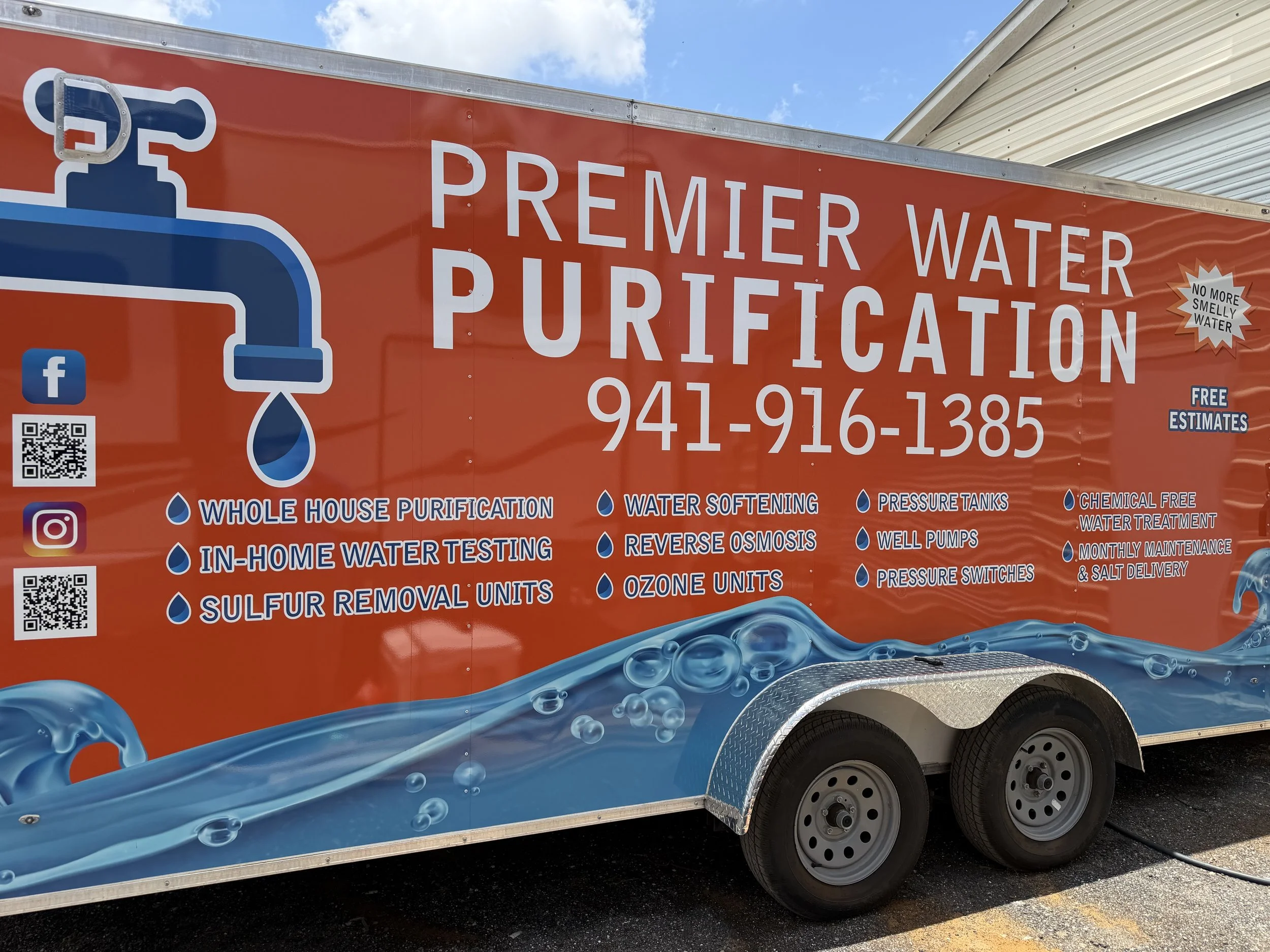 A Bright orange mobile water purification trailer with branding and contact information, featuring icons of water drops and related services. Including well and city water options