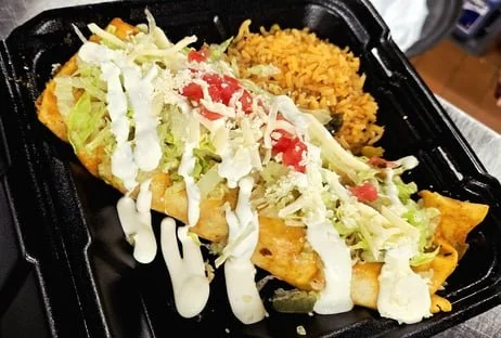 Mexican takeout container with an enchilada topped with lettuce, shredded cheese, and sour cream, alongside Mexican rice.