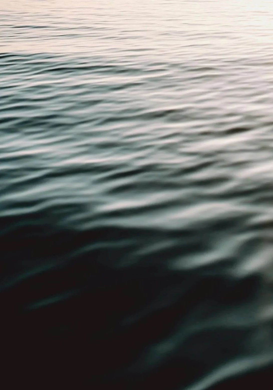 Close-up of water with gentle ripples, possibly at sunset or sunrise.