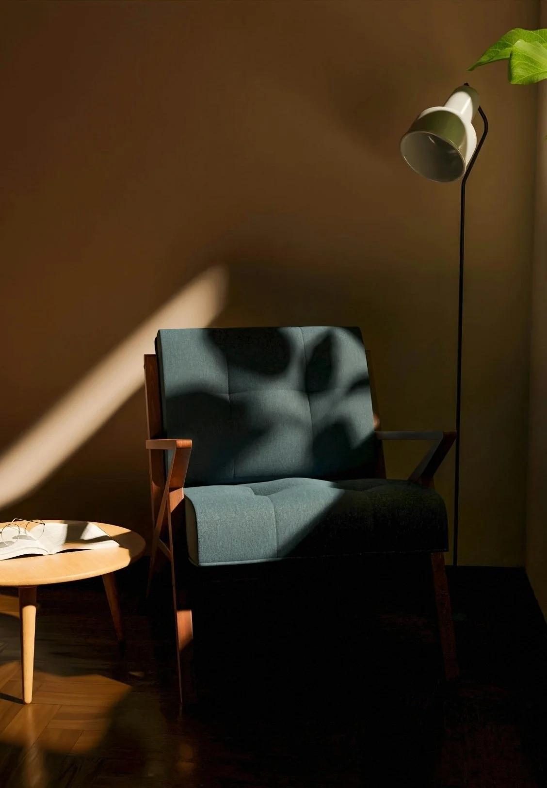 A blue upholstered armchair with wooden armrests and legs, a small round wooden side table with glasses and an open book, a green desk lamp, and a leafy plant, all illuminated by sunlight casting shadows on a brown wall.