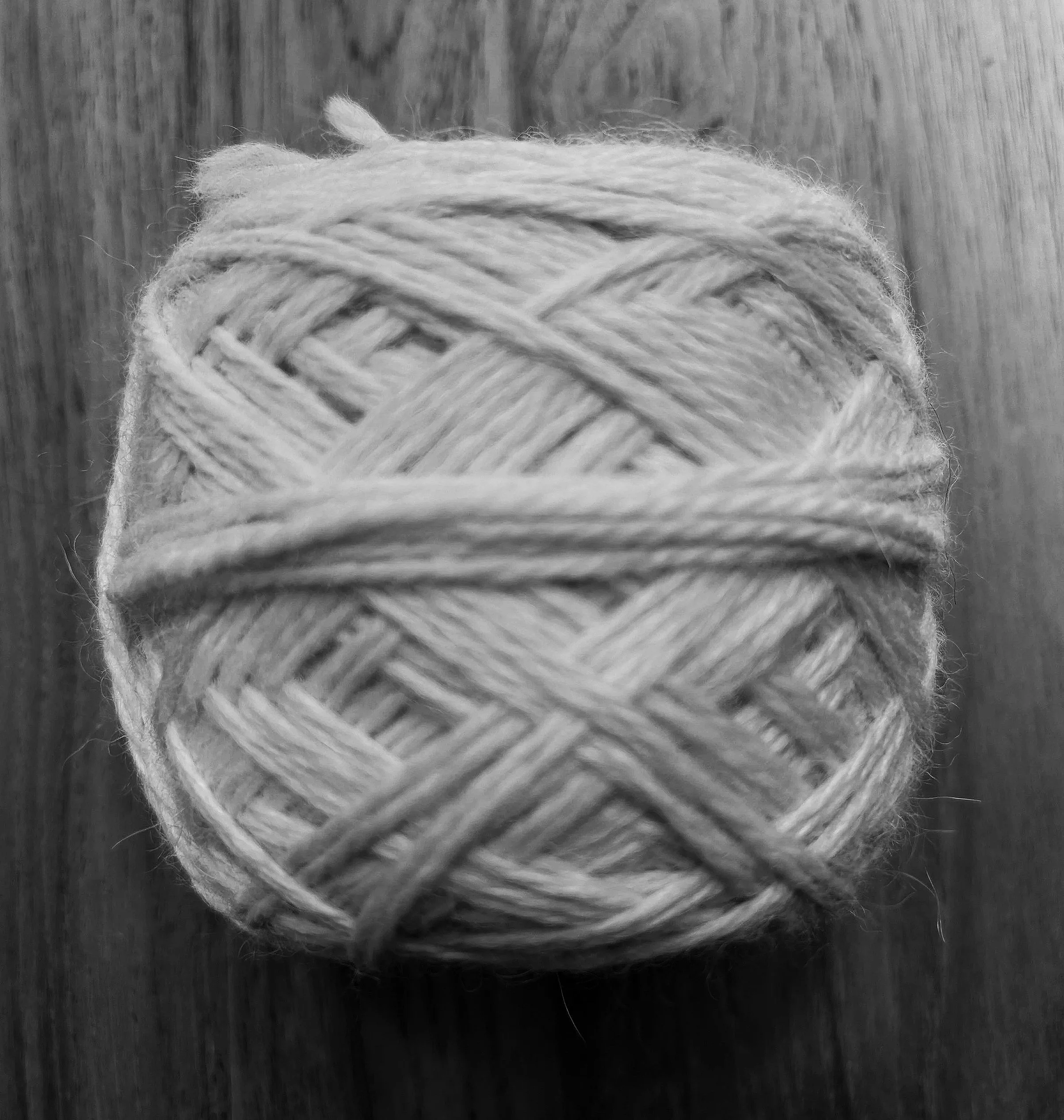 Ball of soft light grey yarn on a wooden surface, for a Tactile Elements DIY knitting kit