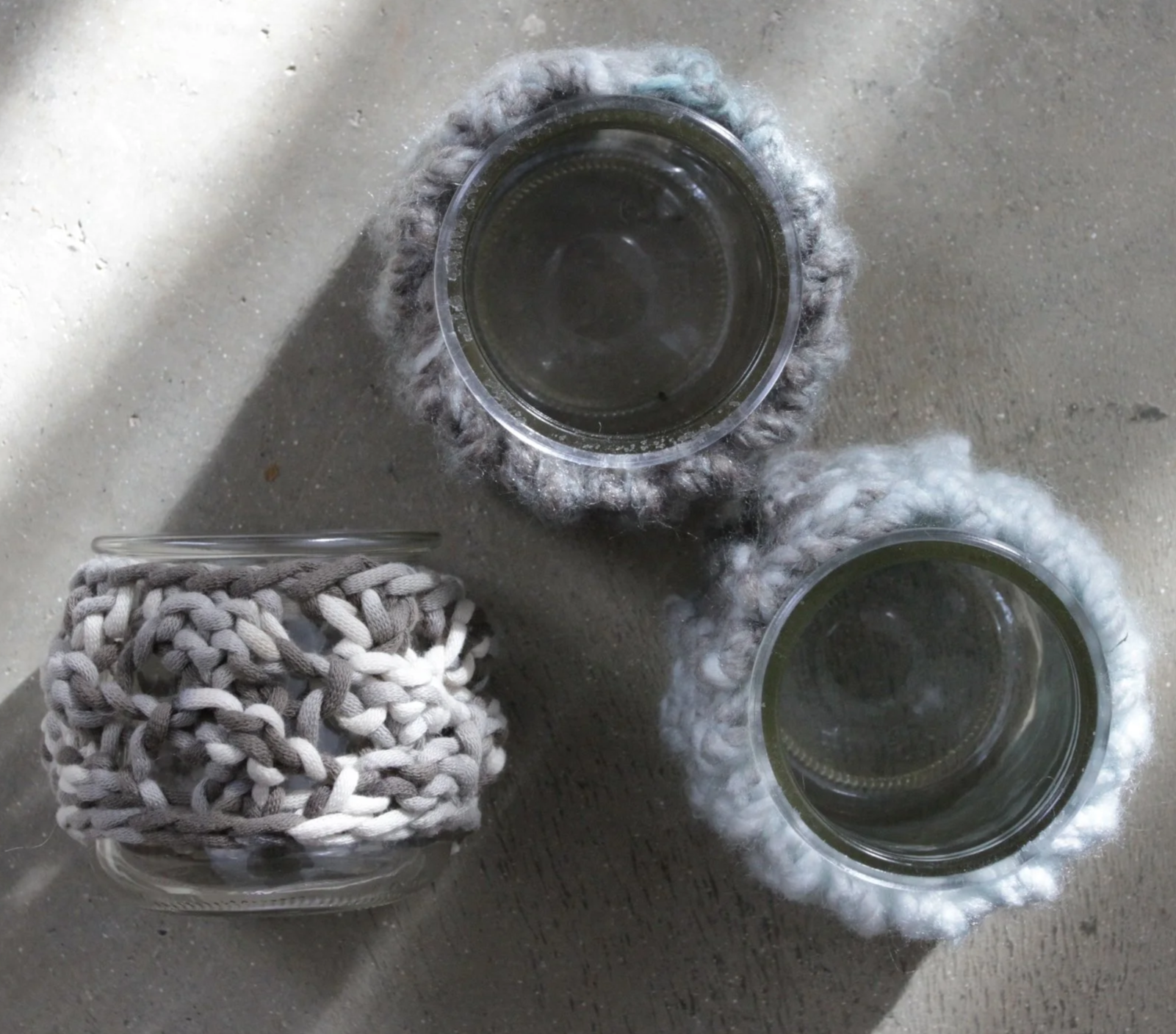 Overhead view of hand-knit coasters next to glass cups, showcasing a Tactile Elements knitting kit project
