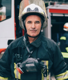 Pompier en tenue de secours avec casque, devant un camion de pompiers.