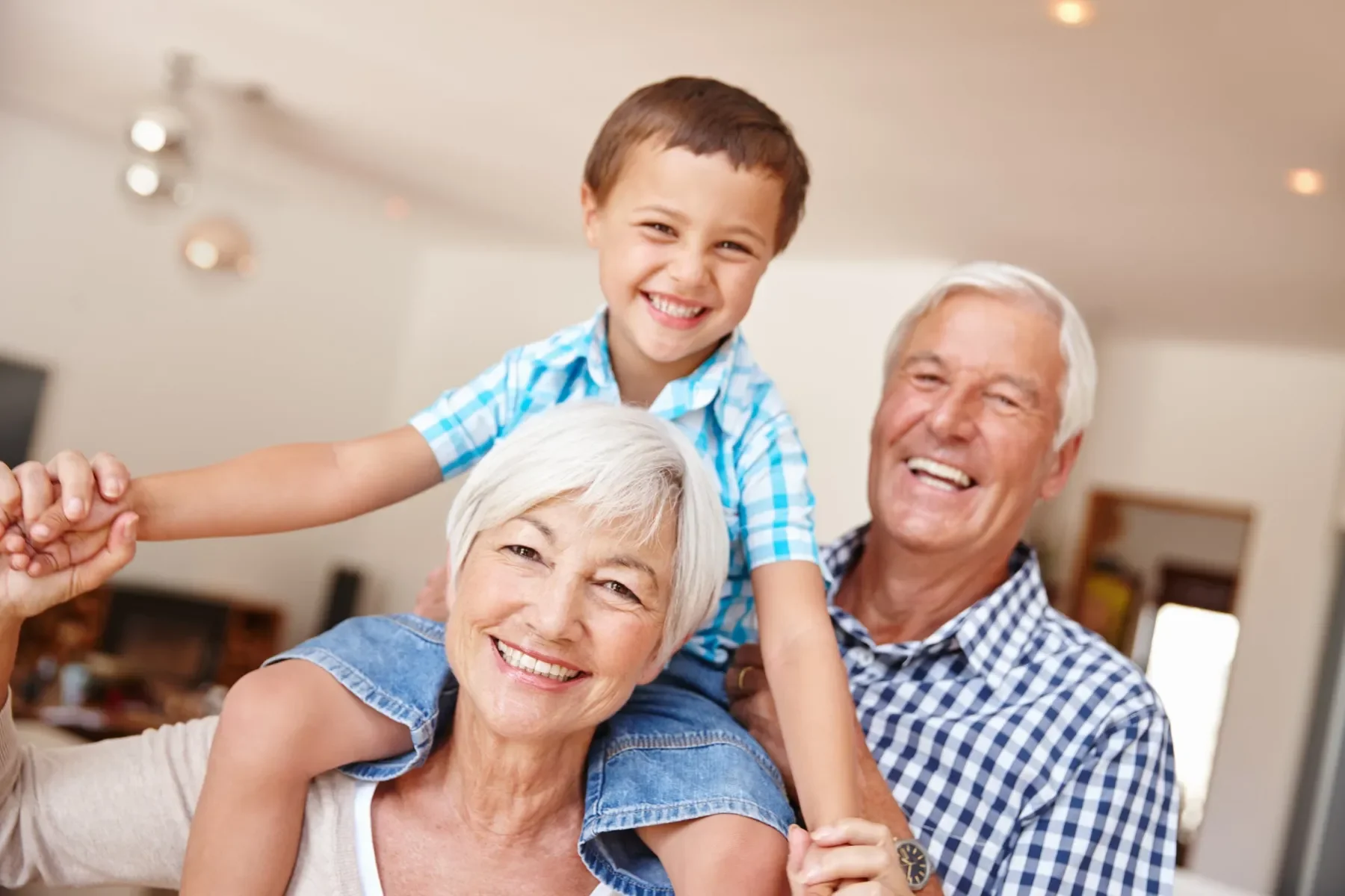 Une famille souriante composée d'une grand-mère, d'un grand-père et d'un petit garçon, tous réunis dans une maison, exprimant la joie et l'affection. Ils sont heureux car ont une bonne audition