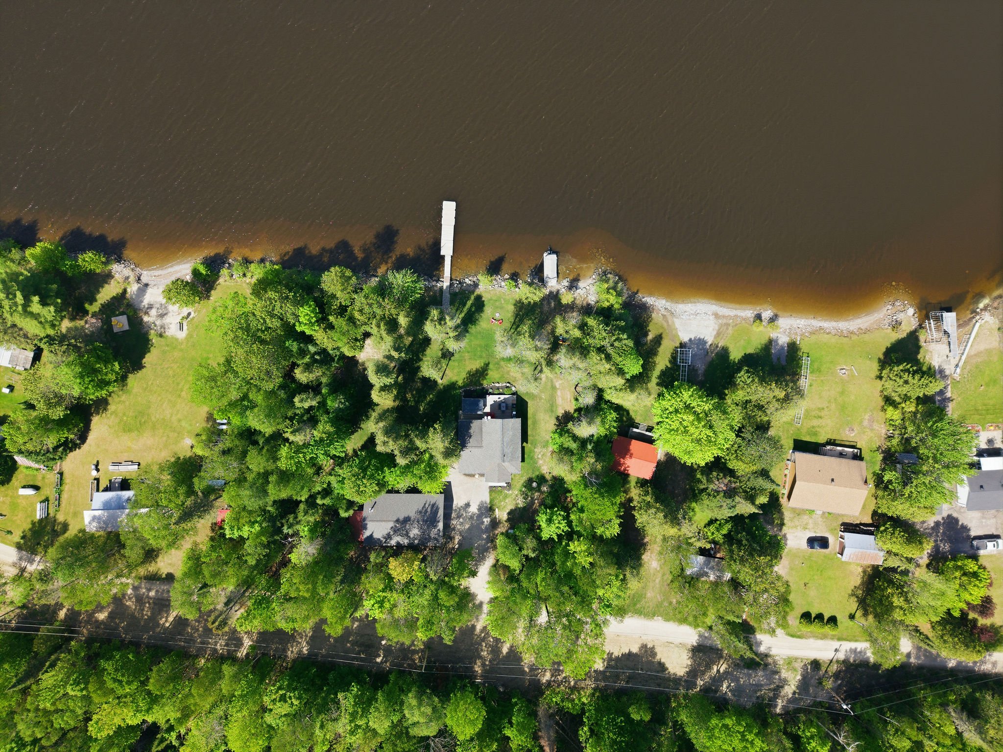 An aerial view of a lakeside residential area with houses, trees, and a shoreline visible.
