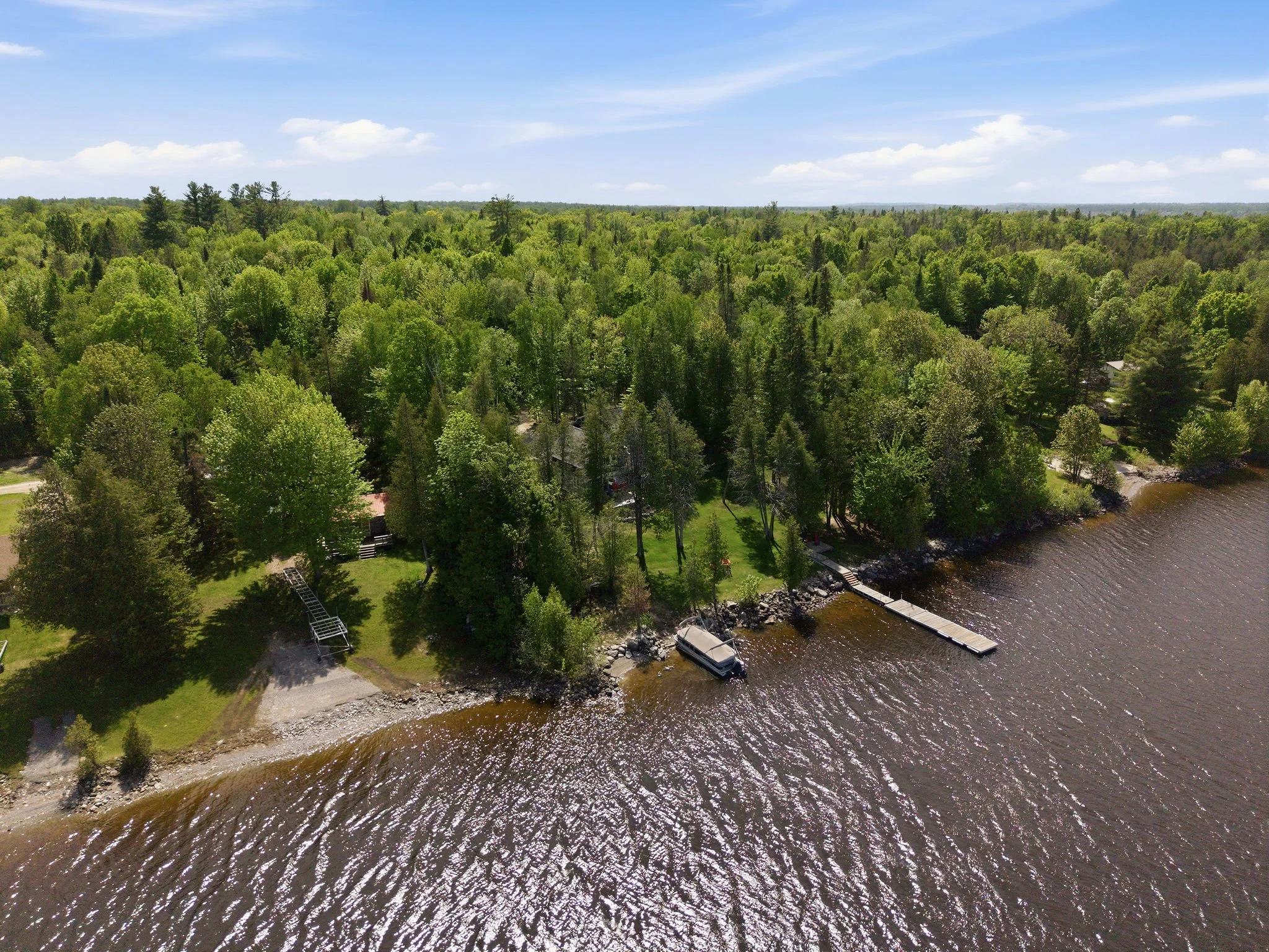 Aerial view of a forested lakeside with a dock and small buildings.