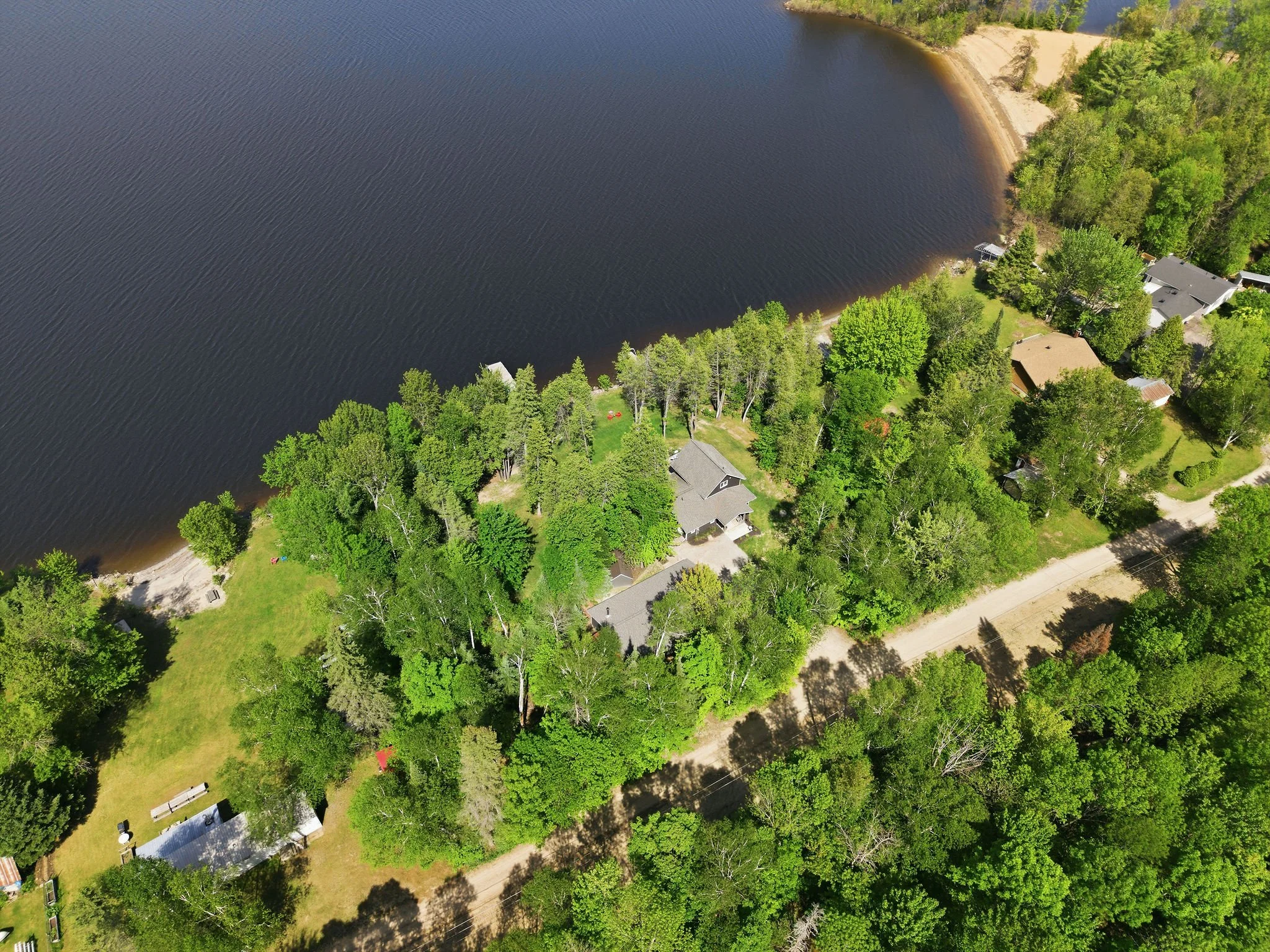 Aerial view of a suburban neighborhood with houses surrounded by green trees next to a large body of water, possibly a lake or reservoir.