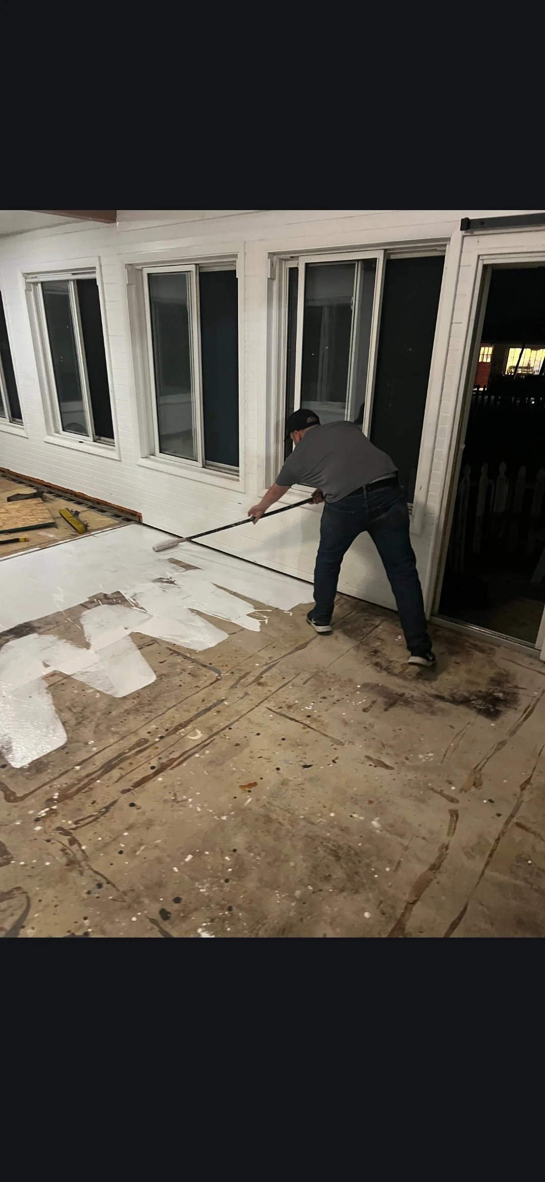 A man applying primer to a subfloor