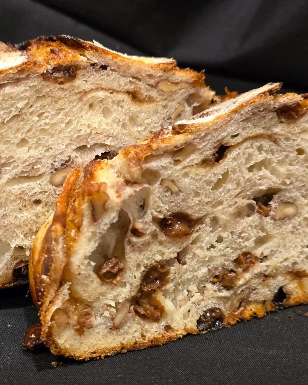 Close-up of a sliced loaf of bread filled with chopped nuts and dried fruits.
