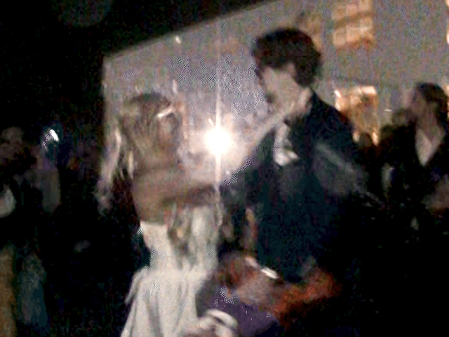 A couple does the grand exit from their wedding, filmed on an old vintage camcorder
