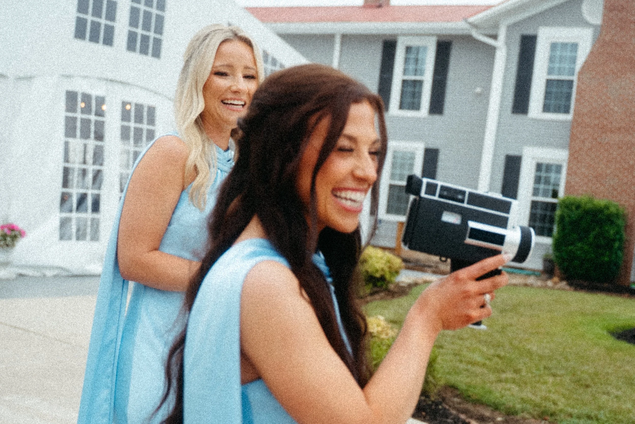 Two bridesmaids using a super 8 style camcorder to film a wedding
