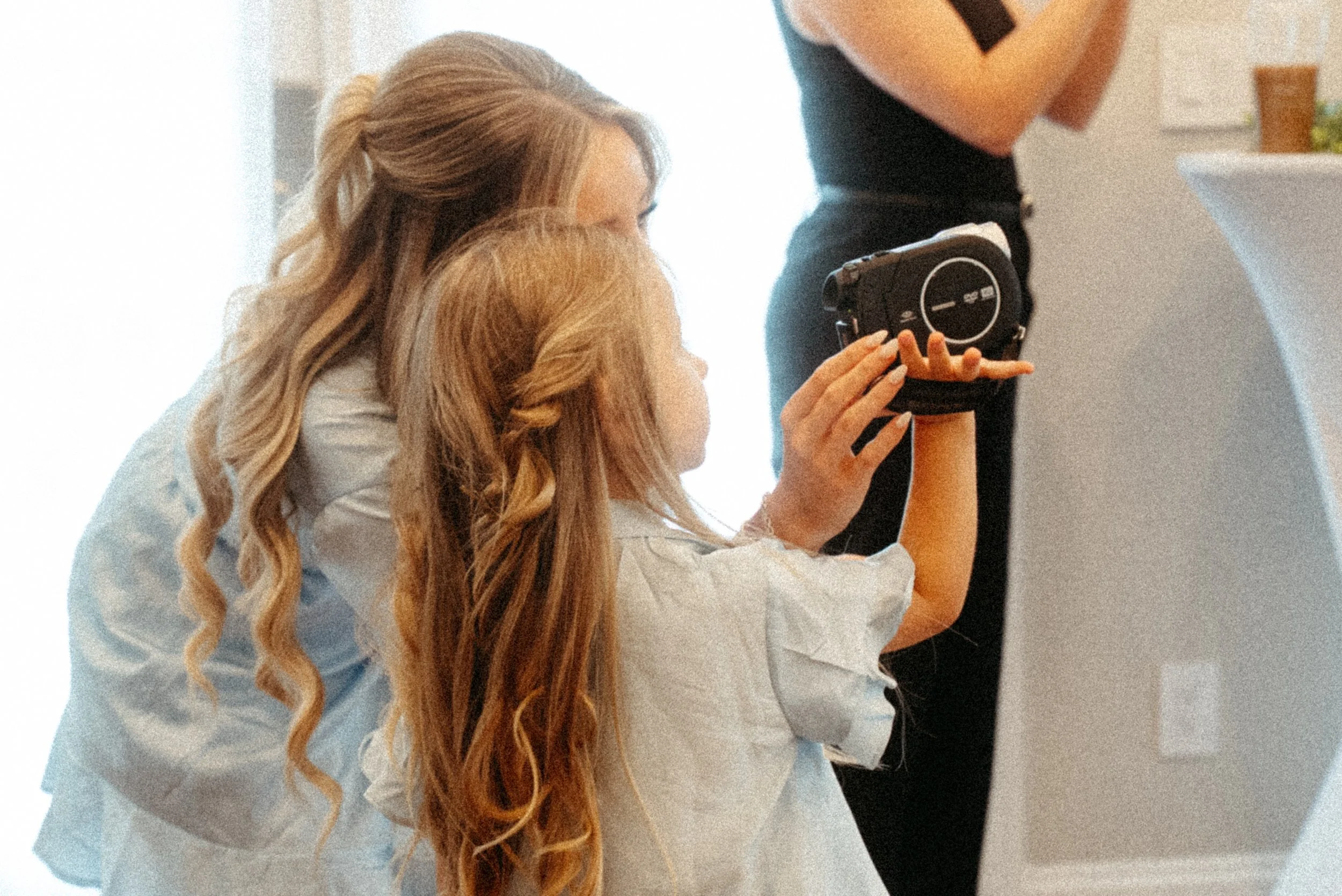 A young child using a camcorder to film a wedding day. The bride is getting ready and the kid is filming