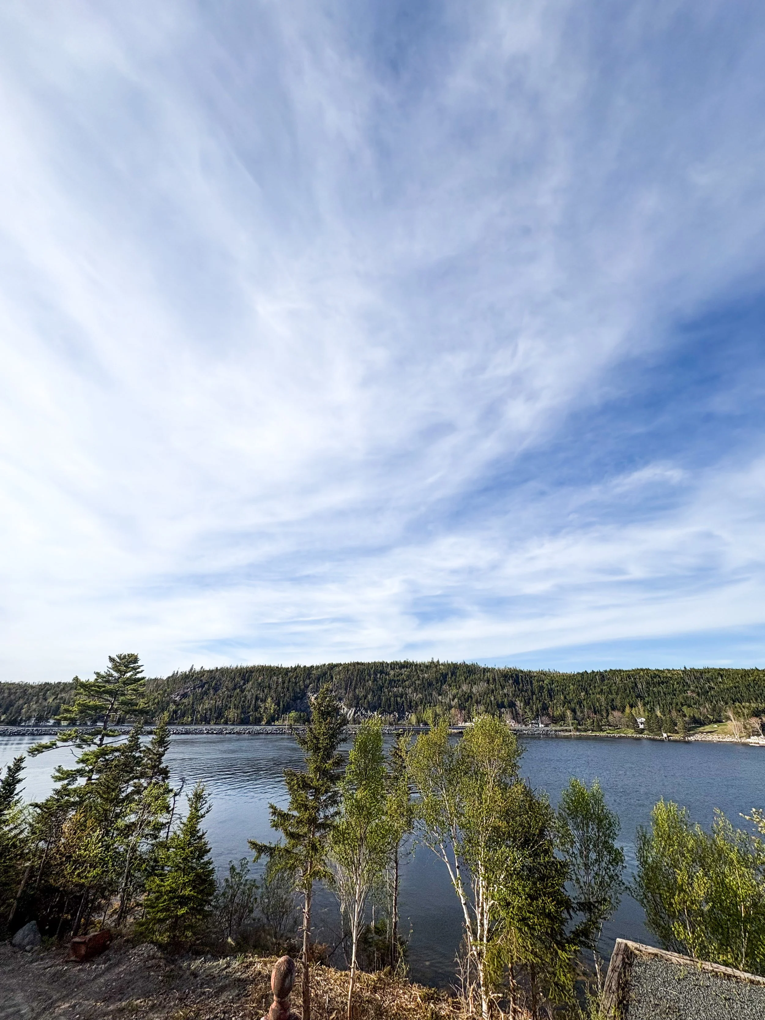 Scenic view of the Jeddore Harbour Inlet from Grand Shores wedding venue, with a forested hill in the background and a partly cloudy sky above.
