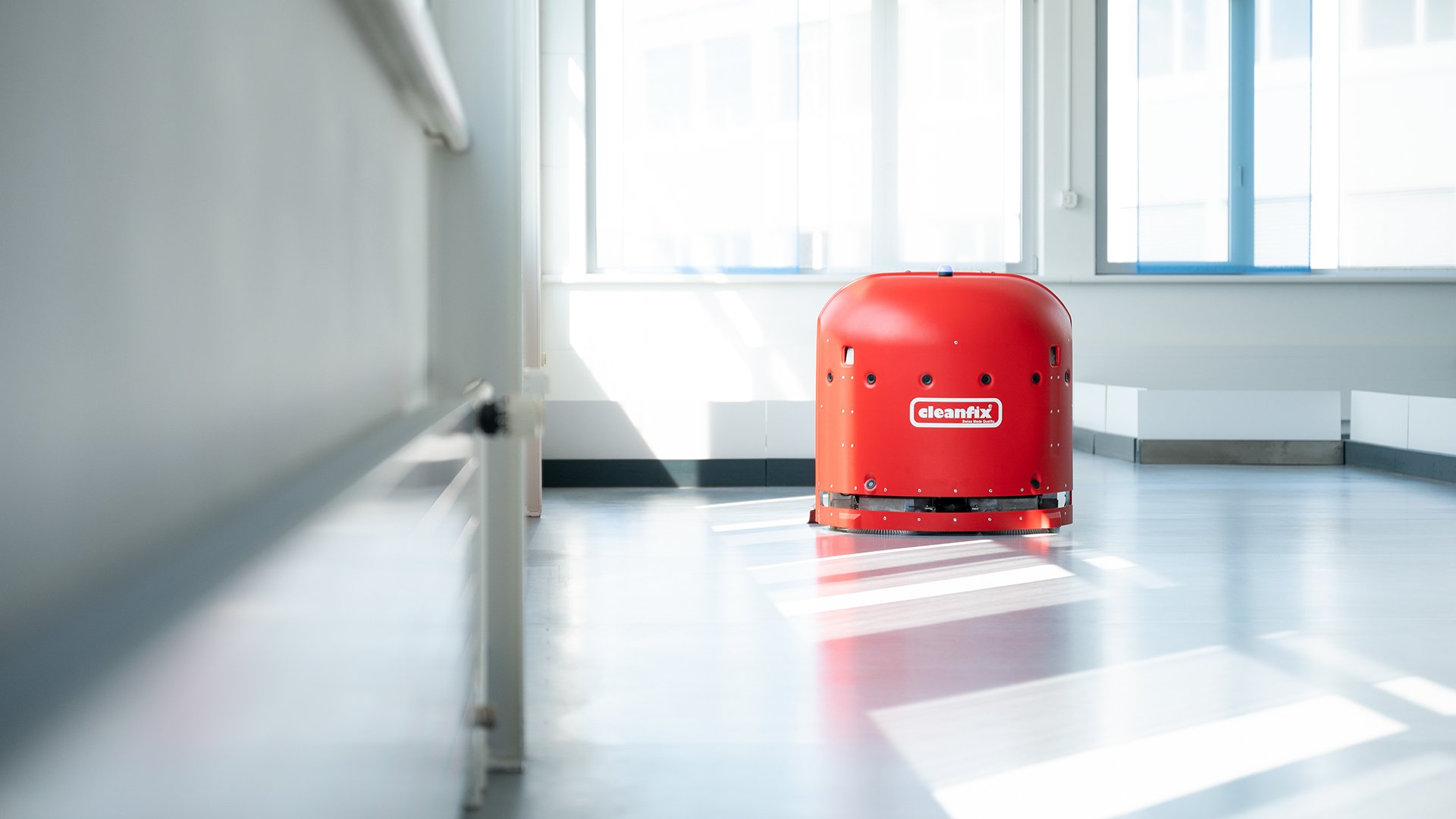Red robotic cleaning machine with 'cleanfix' logo in a brightly lit room.