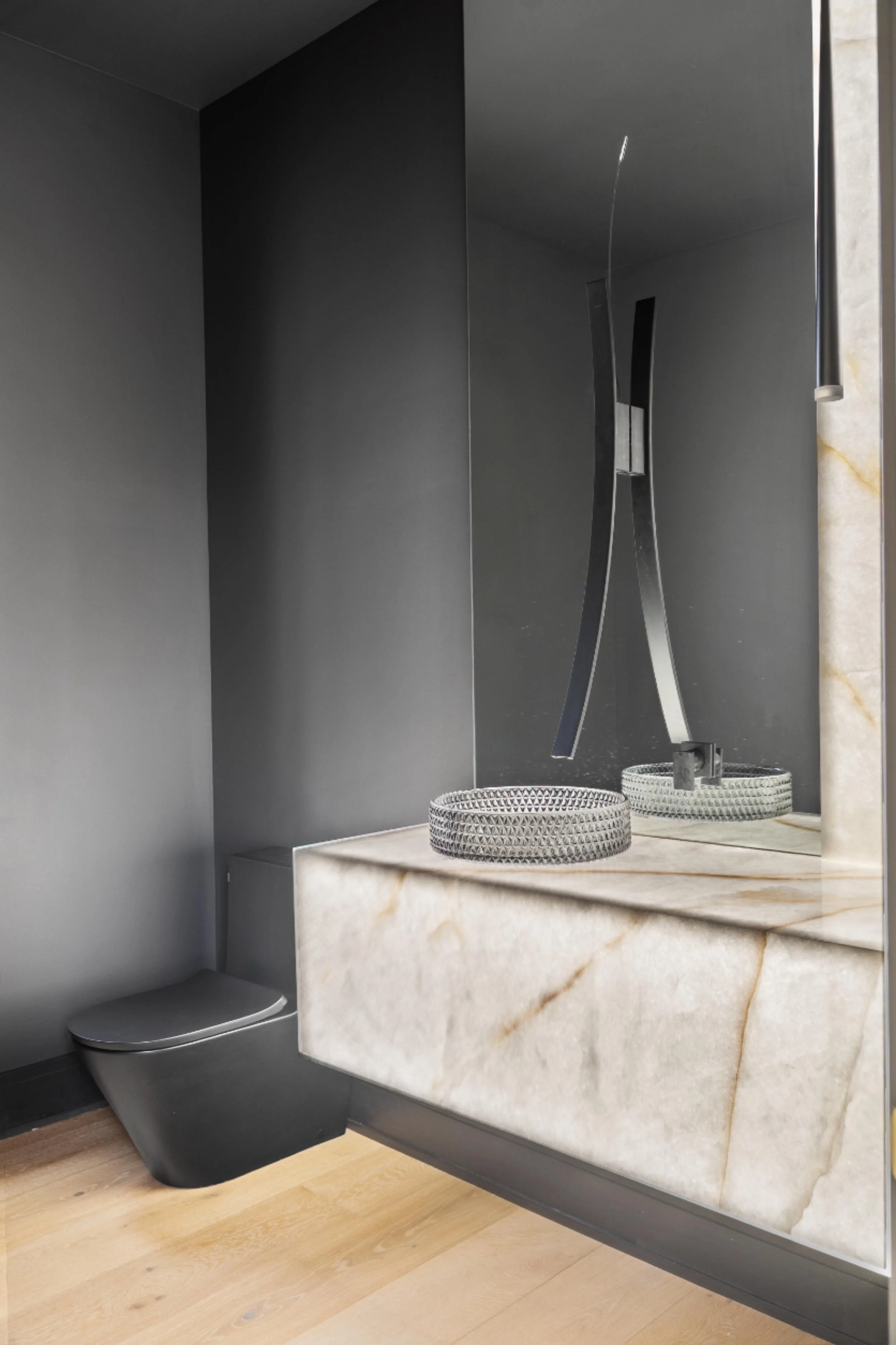 Modern bathroom with a black toilet, marble countertop with two decorative baskets, dark wall, and a mirror with shelf.