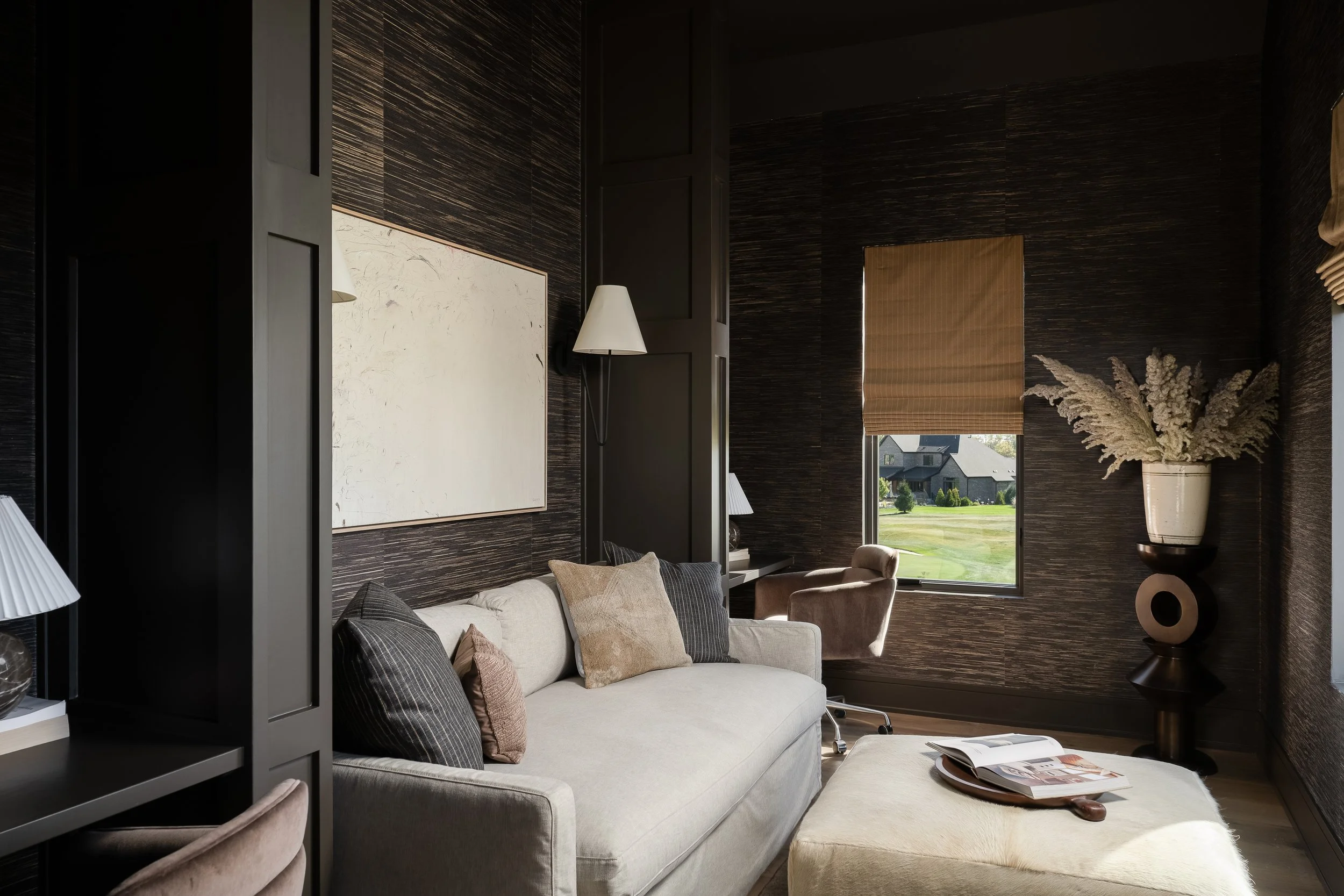 A cozy lounge space featuring dark textured walls and layered neutrals bring depth and warmth.