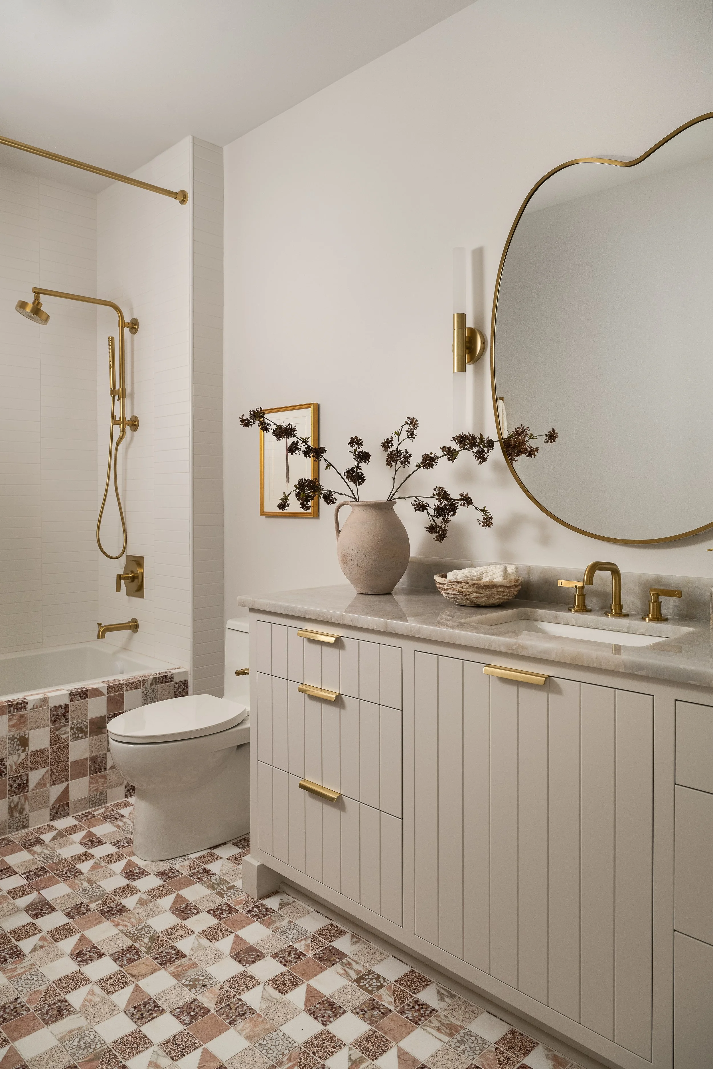 A collected mix of patterned tile, warm brass fixtures, and vertically detailed cabinetry. 