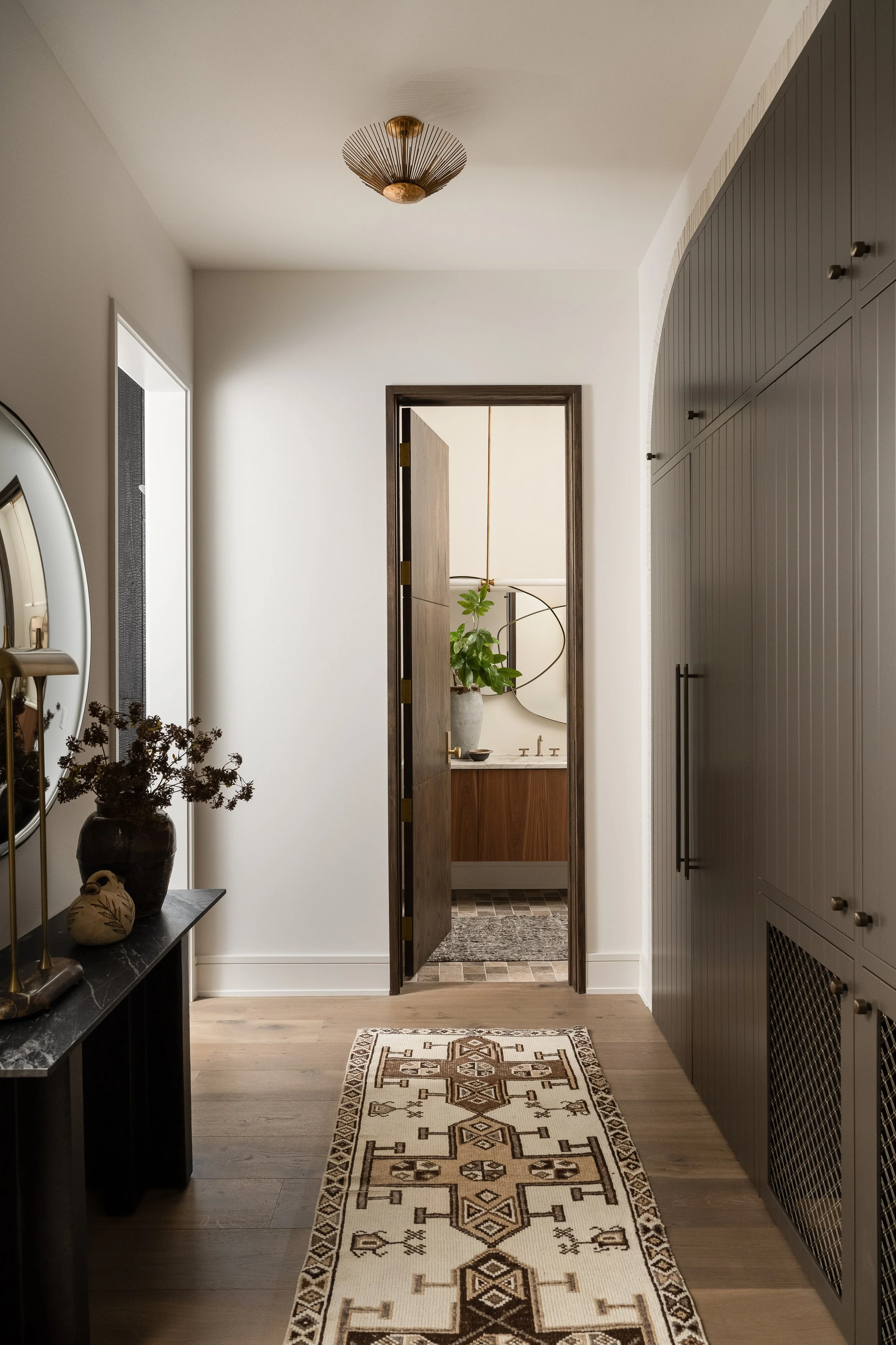 Mudroom featuring vertical millwork, integrated storage, layered textures, and contrasting tones.