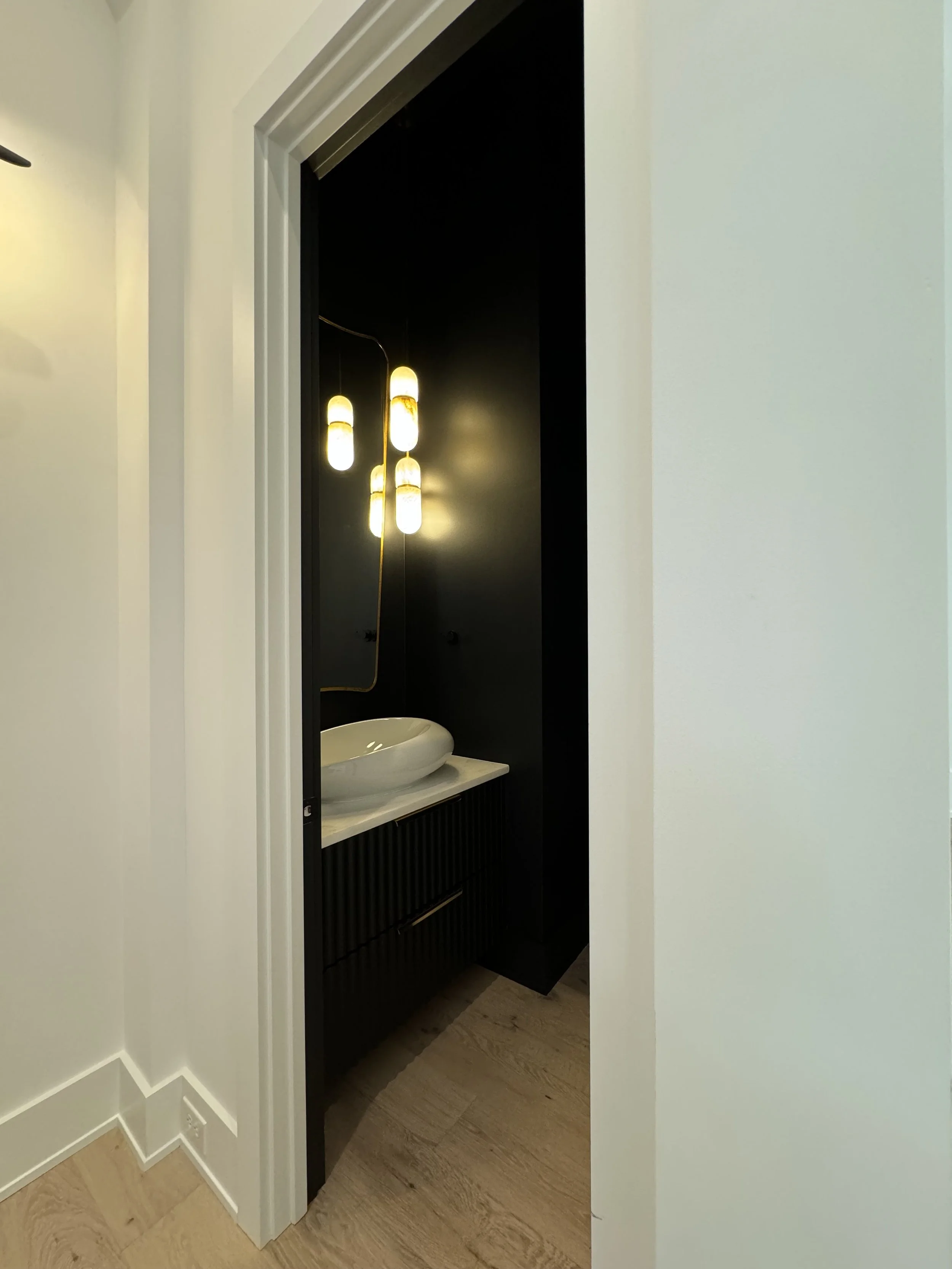 Modern bathroom sink with black vanity and unique pendant lighting