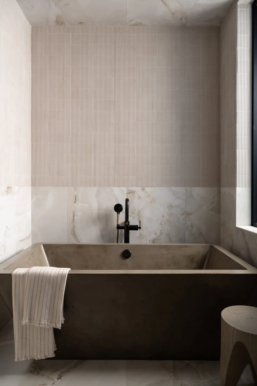 Layered stone and vertical texture create a quiet, sculptural wet room.