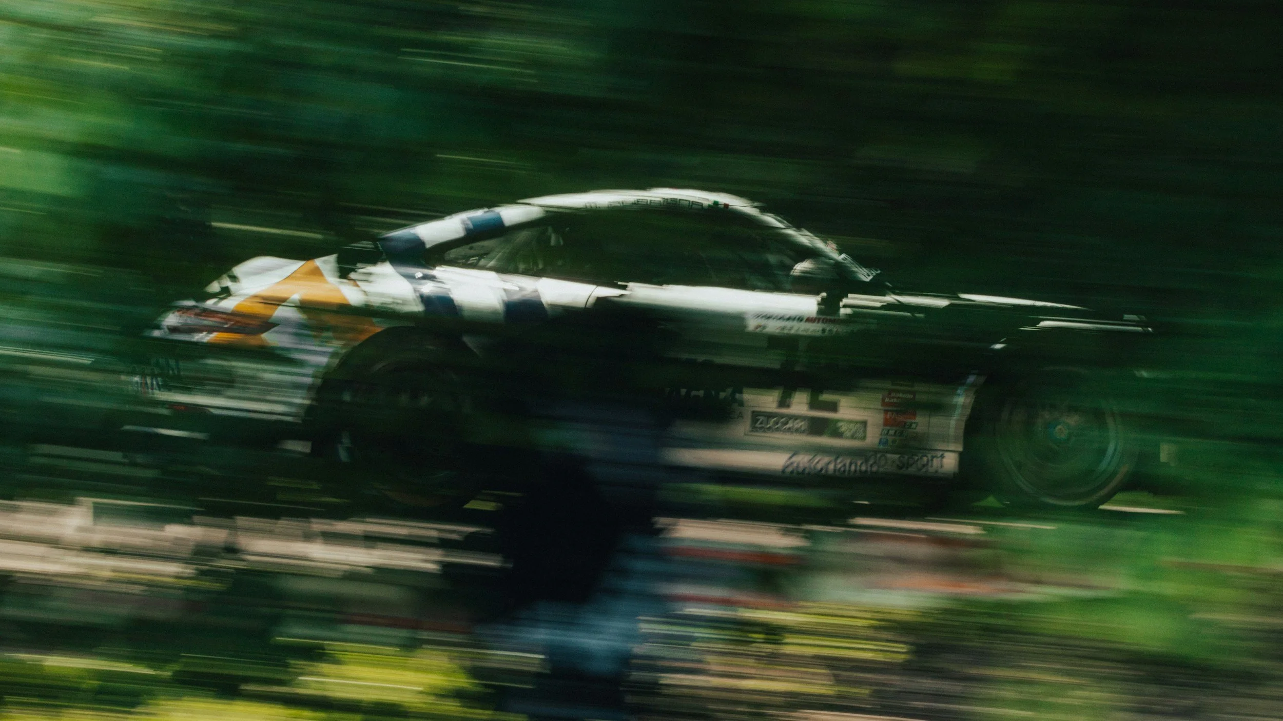 A race car speeding on a track, with motion blur and a road background. dedicated program manager machine shop