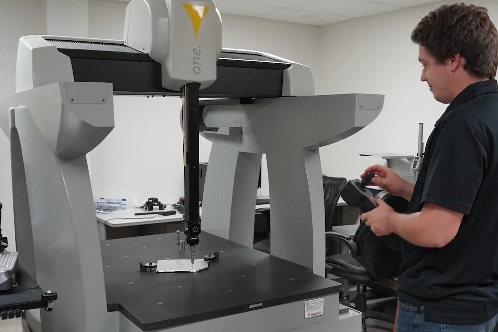 A man operating a large coordinate measuring machine in a laboratory or workshop. scanning and reverse engineering machine shop