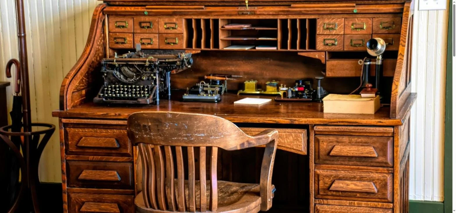An old oak roll top desk and wooden chair in a traditional office