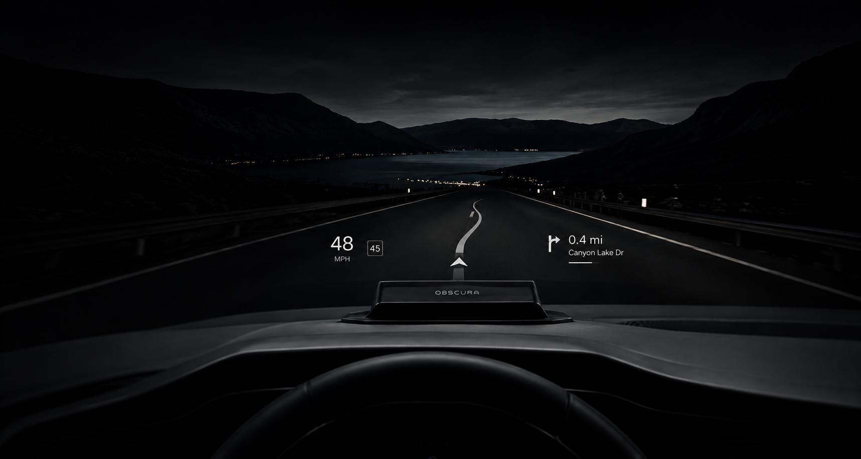 A nighttime view from inside a car showing a digital heads-up display with navigation directions, speed of 48 MPH, and the road ahead leading towards a lake with surrounding mountains.