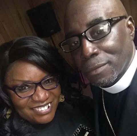 A man and woman wearing glasses taking a selfie together indoors.