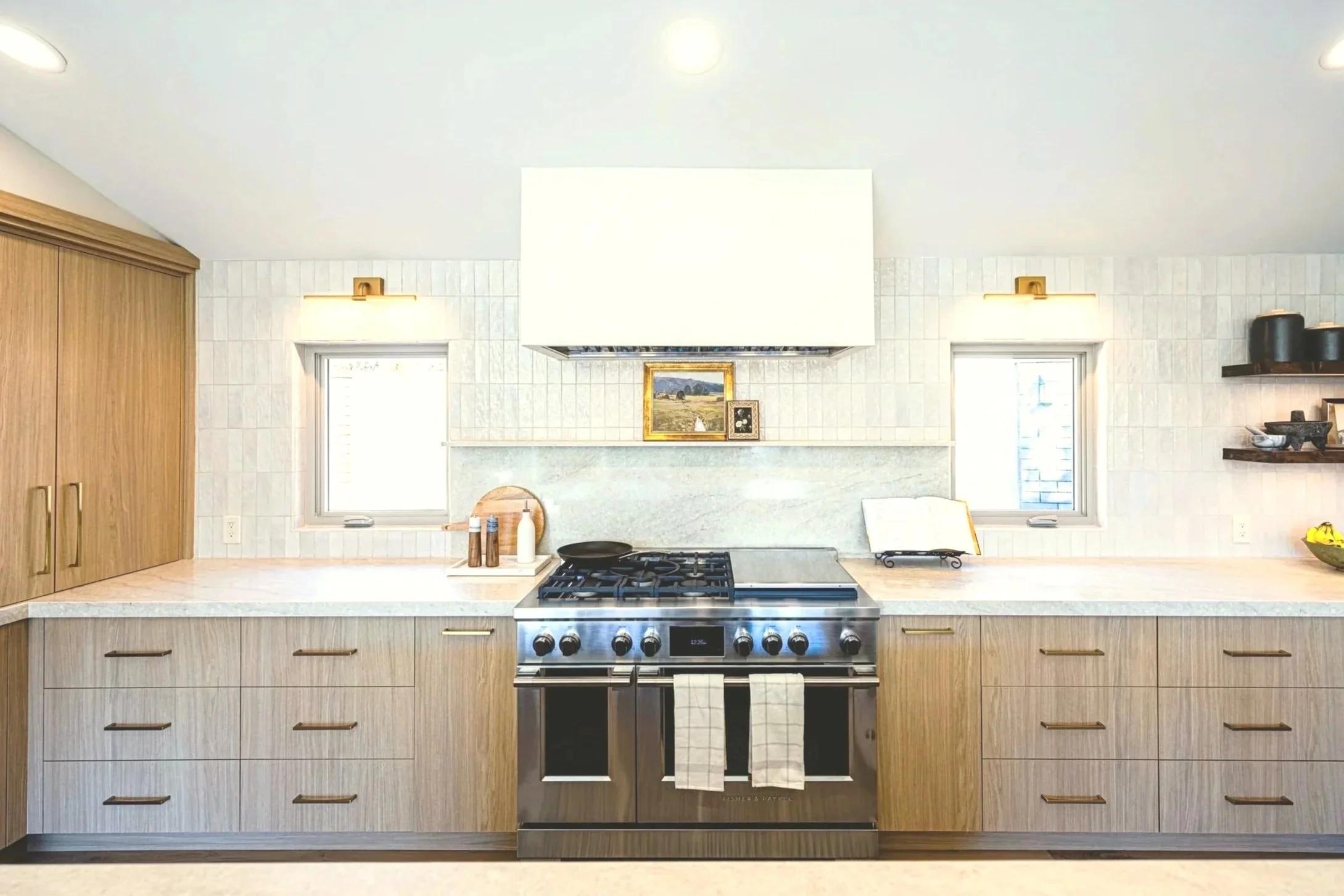 Kitchen with wooden cabinets, a stove, and decorative items on shelves, with two windows above the counter