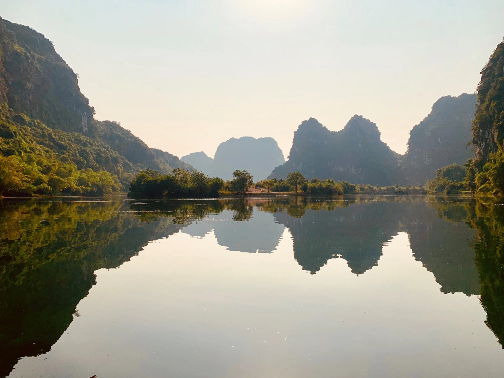 A serene river scene with mountains on either side and calm water reflecting the landscape in Vietnam.