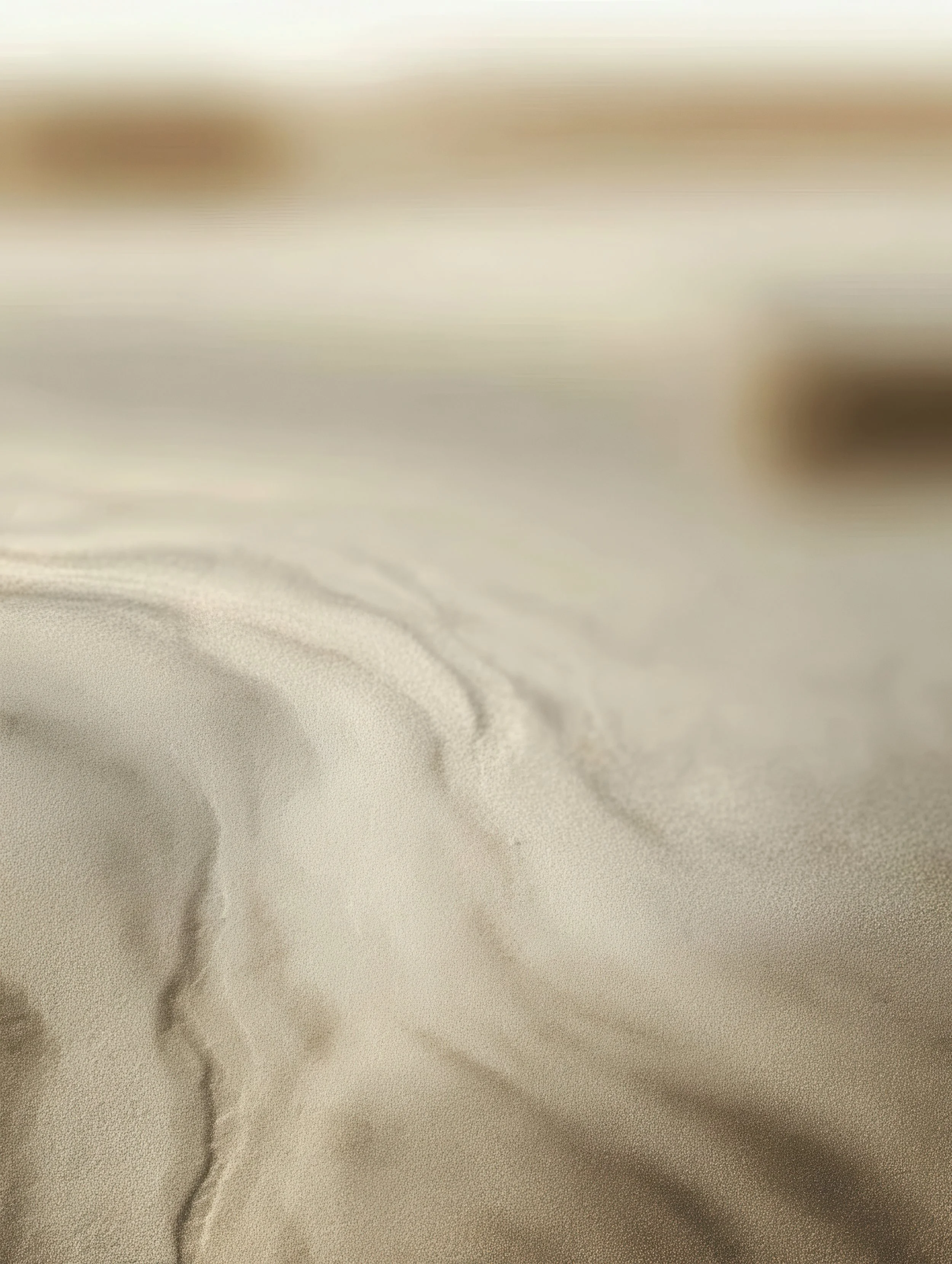 Close-up of a beige and cream-colored satin or silk fabric with soft folds and a smooth texture.