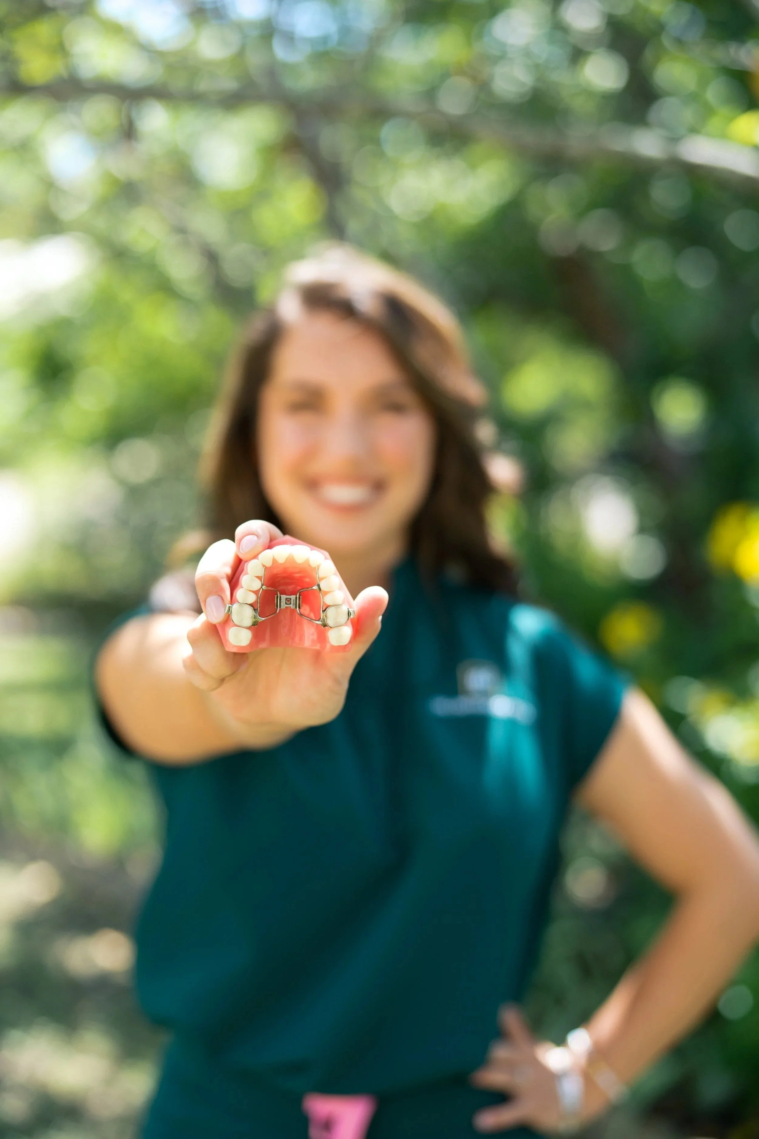 Dr. Avery Gil holding a dental model with a palatal expander in focus, demonstrating early interceptive orthodontic treatment options in Dripping Springs.
