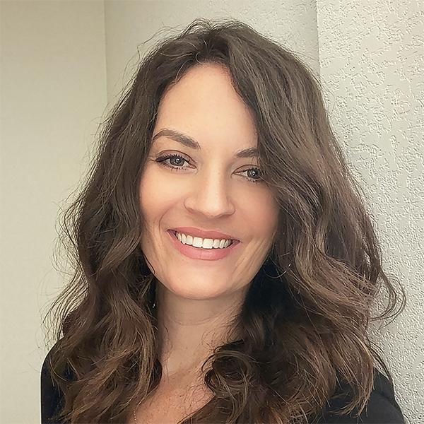 A smiling adult woman with beautiful, straight teeth, representing successful clear aligner treatment at Gil Orthodontics in Dripping Springs.