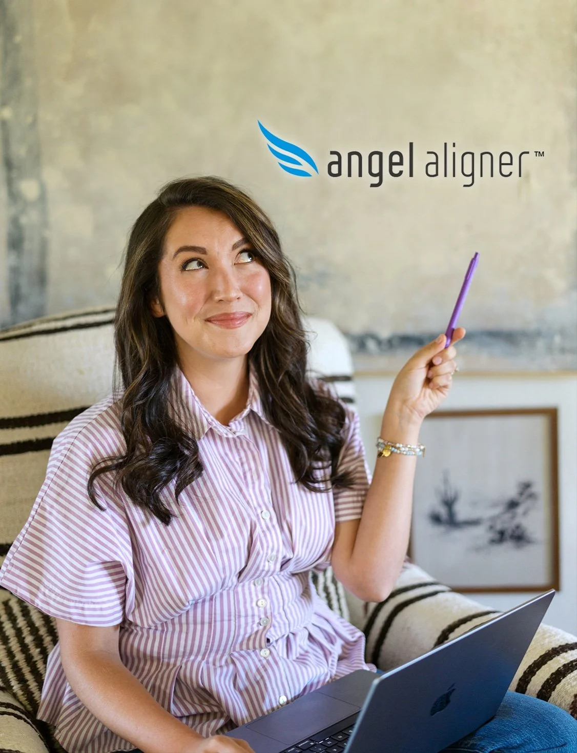 Dr. Avery Gil smiling and pointing her pen toward the Angel Aligner logo, representing clear aligner treatment options at Gil Orthodontics in Dripping Springs.