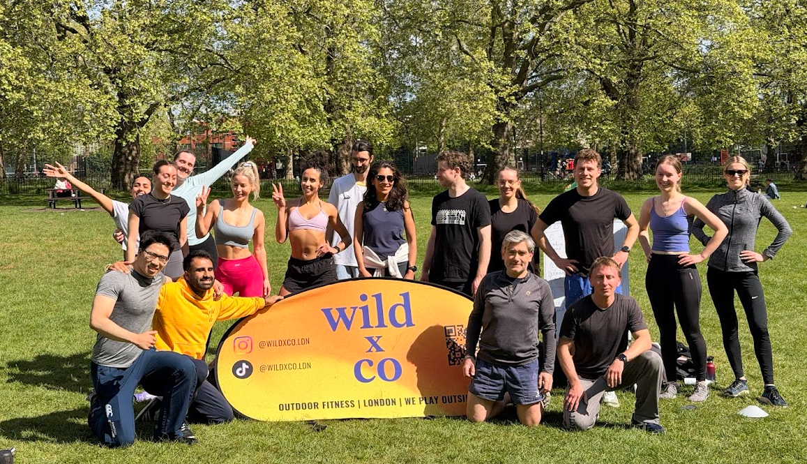 post workout from wild LDN outdoor group workout in Highbury Fields, Islington - a group of young, athletic people sweaty and very happy after the outdoor fitness group class in a beautiful London park on a stunning, blue sky summers day