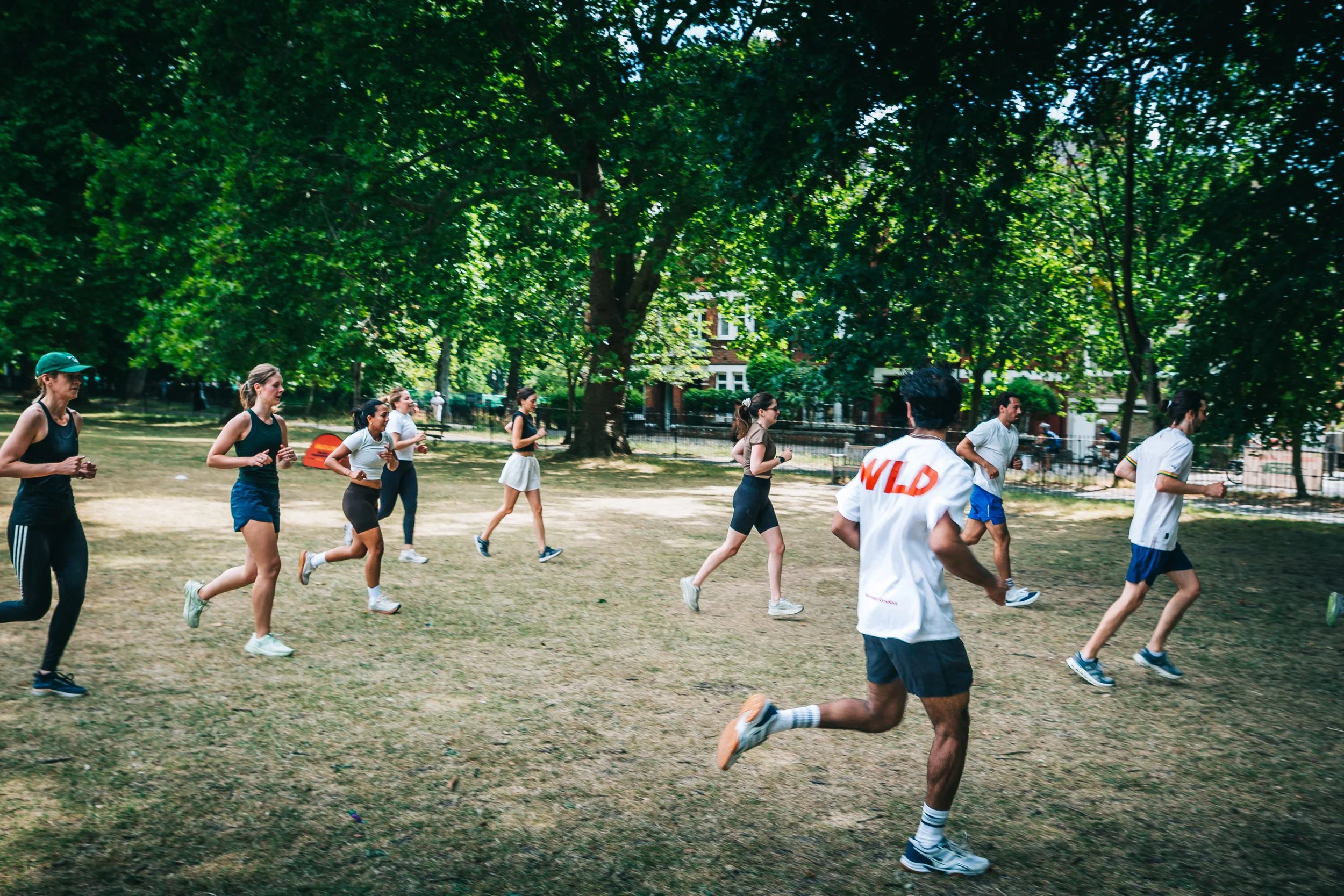 post workout from wild LDN outdoor group workout in Highbury Fields, Islington - a group of young, athletic people sweaty and very happy after the outdoor fitness group class in a beautiful London park on a stunning, blue sky summers day