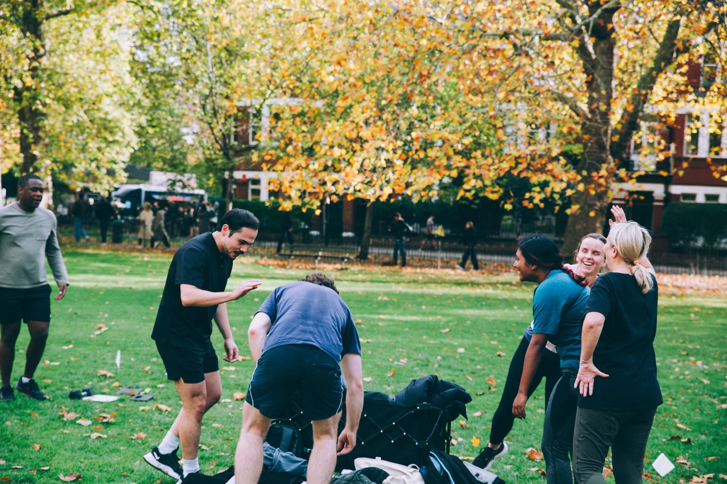 team picture from after a wild LDN session in Highbury Fields, Islington - a group of young, athletic people in their 20s and 30s sweaty and happily chatting away during the outdoor fitness group class. there's equipment too
