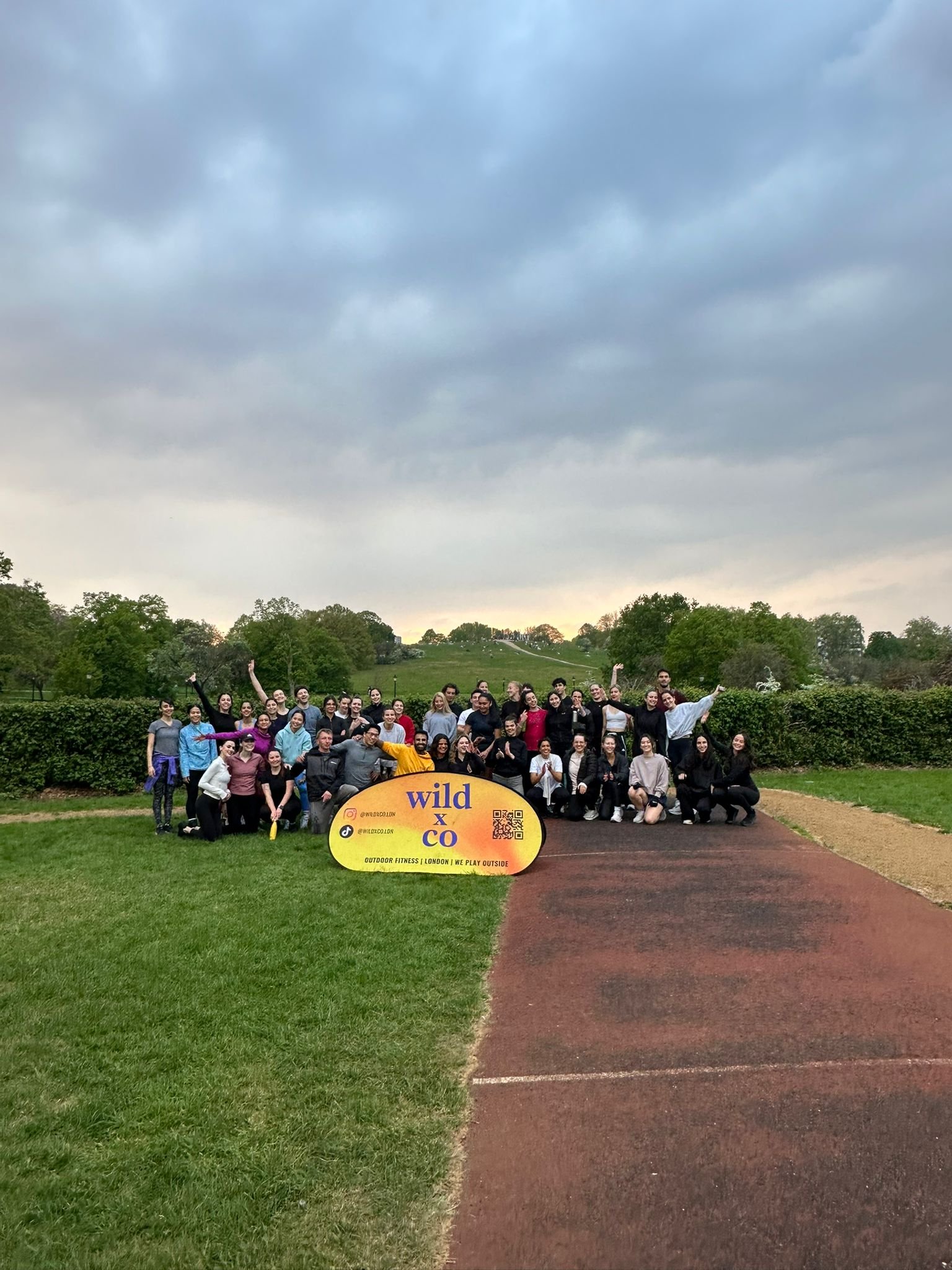 team photo after a wild LDN outdoor workout in Primrose Hill, Regents Park - about 45 young, athletic people sweaty and very happy after the outdoor fitness group class in a beautiful London park on a stunning evening at sunset
